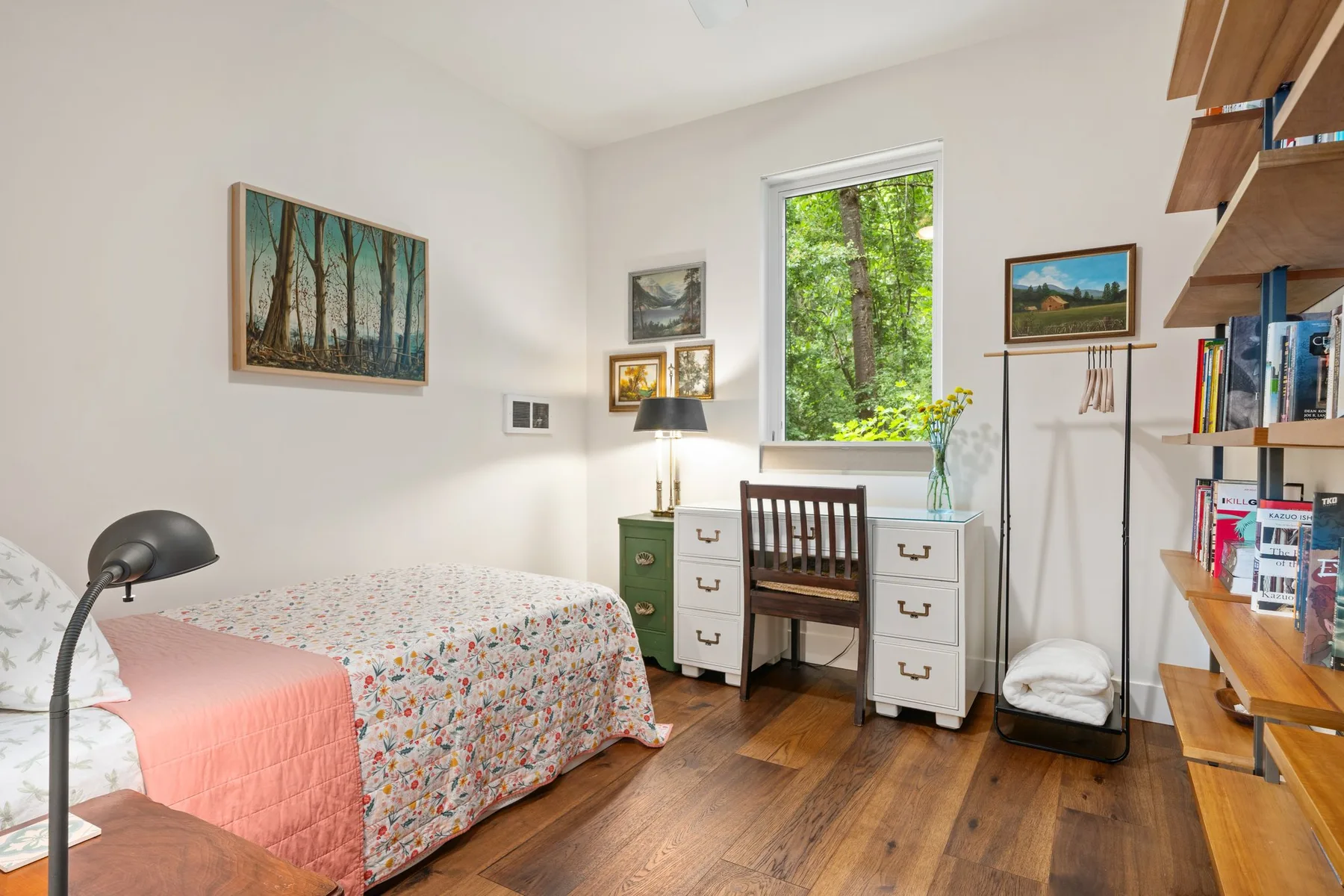 Dormitorio con cama, escritorio y una gran ventana con árboles a la vista.