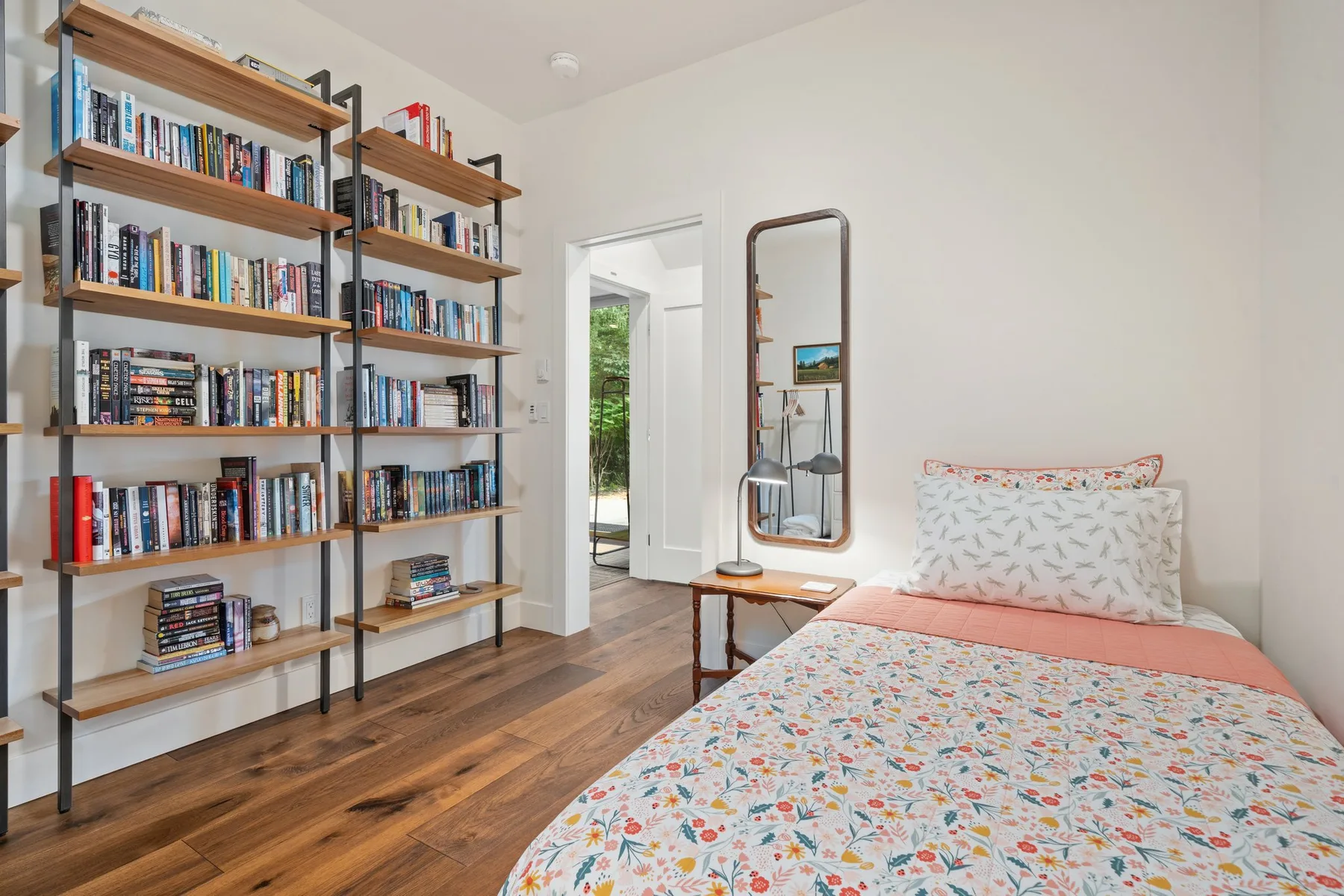 Un dormitorio con una cama junto a estanterías altas llenas de libros.