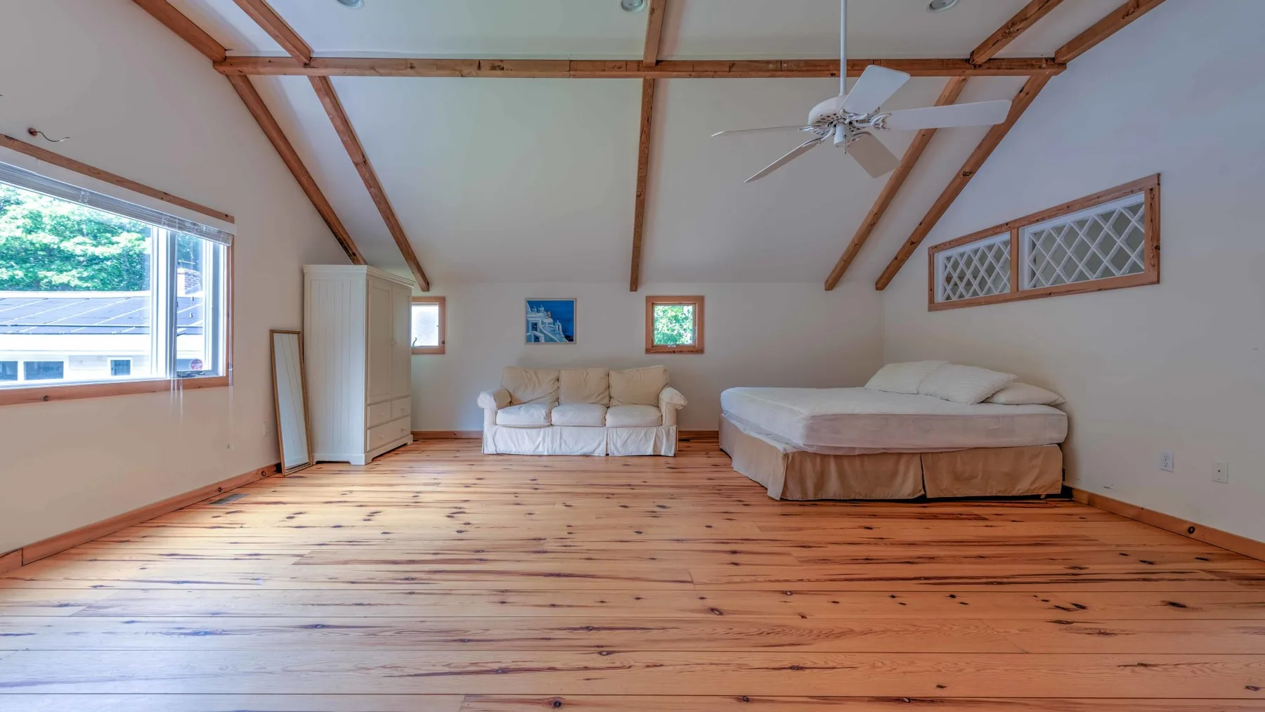Un dormitorio amplio con una cama, una zona de estar y vigas de madera expuestas en el techo.