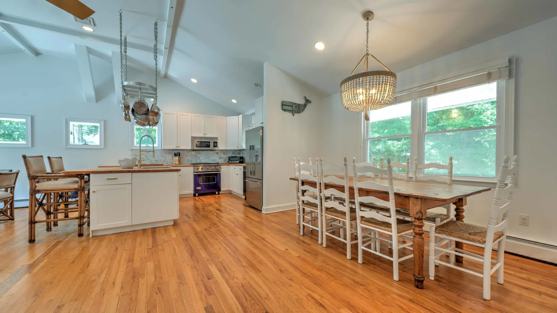 Una cocina abierta y zona de comedor con una mesa de madera y sillas blancas.