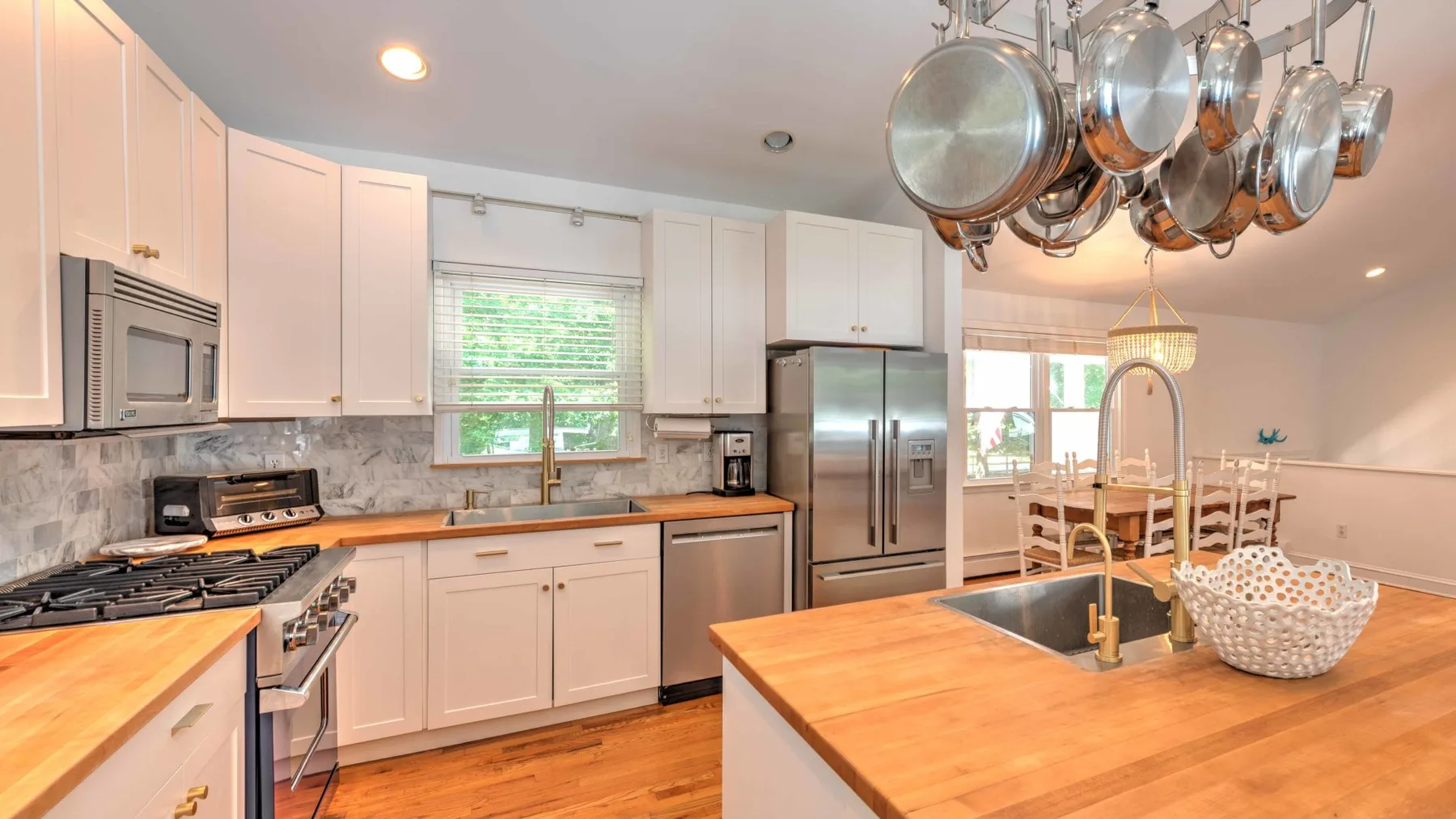 A bright kitchen with white cabinets, stainless steel appliances, and a large island.