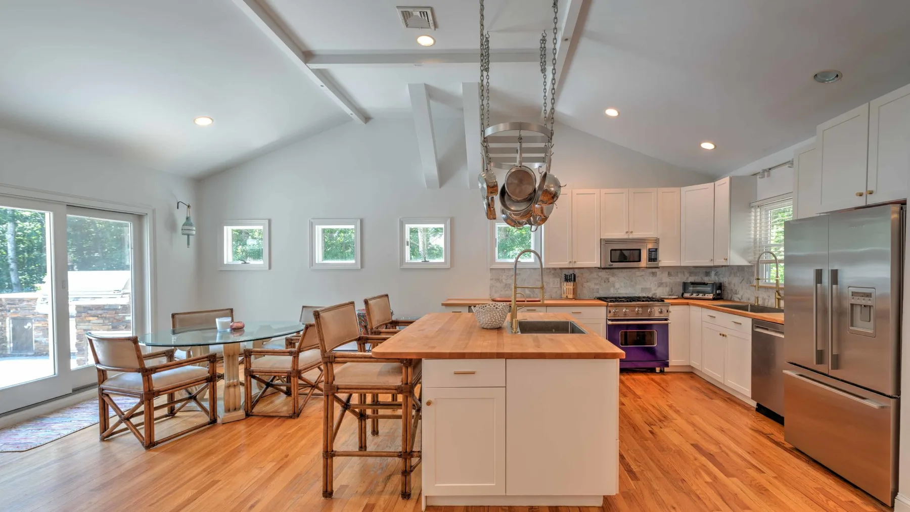 Una cocina y comedor luminosos con una isla central y suelo de madera.