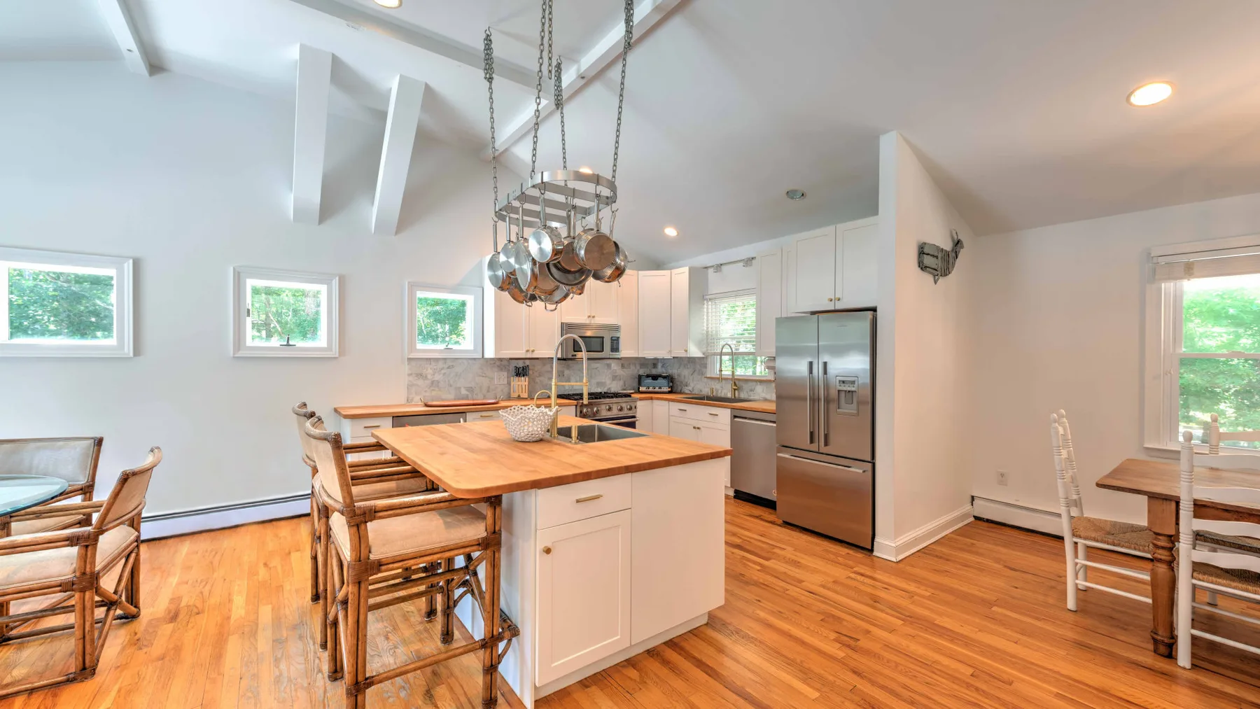 A bright kitchen with a large island and wooden dining table.