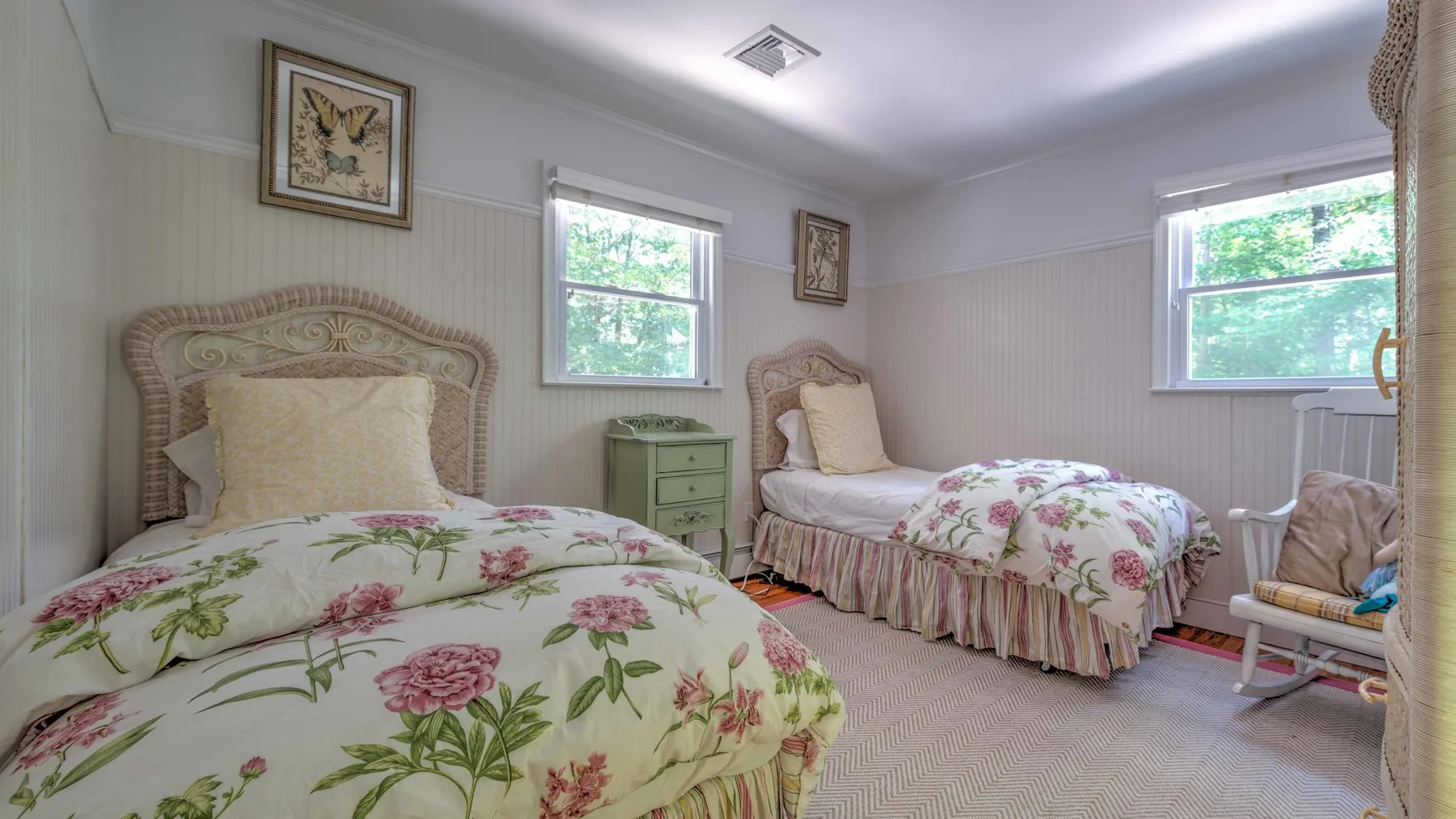 Un dormitorio con dos camas cubiertas con ropa de cama floral y ventanas.