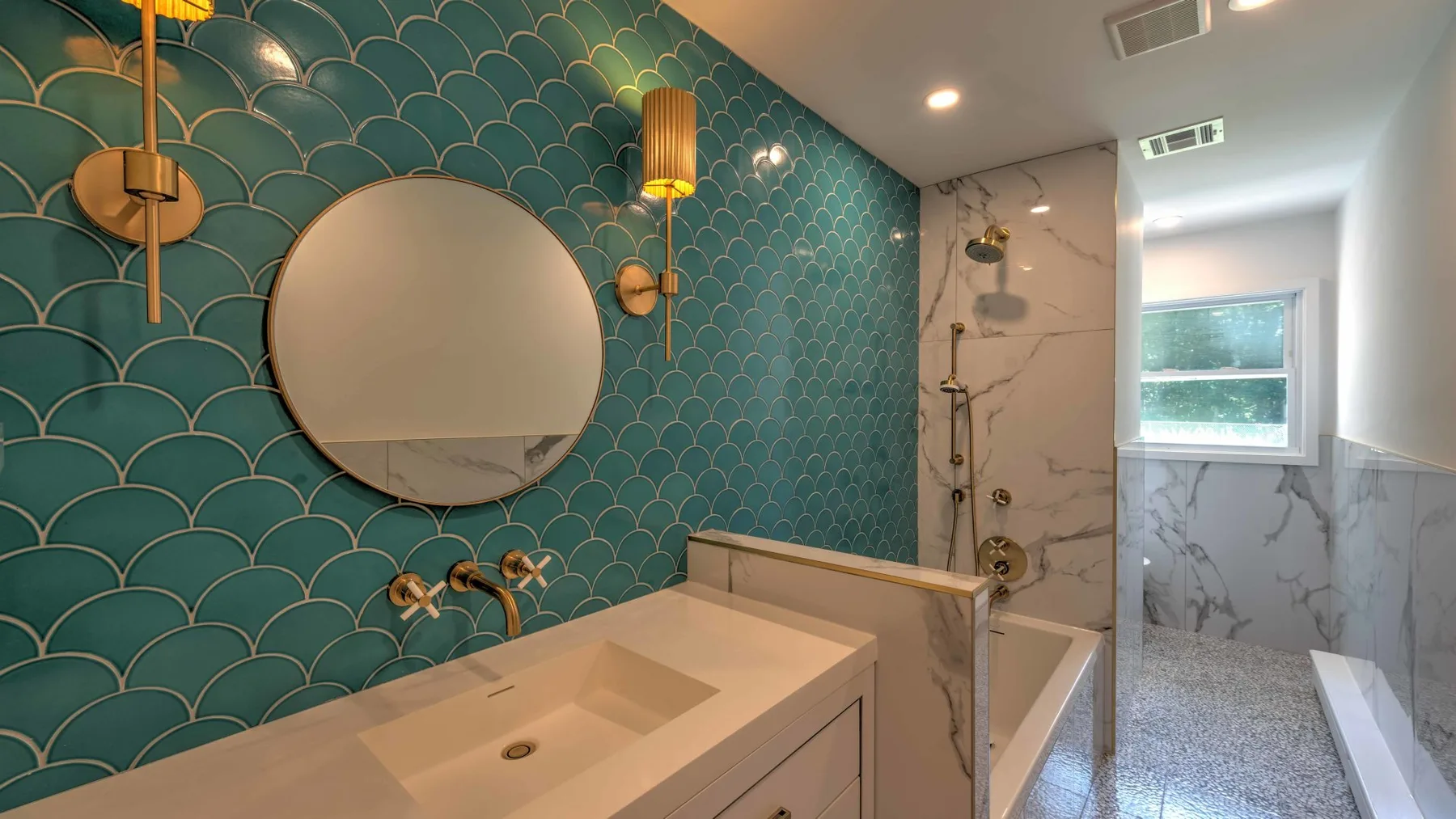 Un baño con lavabo, espejo redondo y zona de ducha con azulejos.