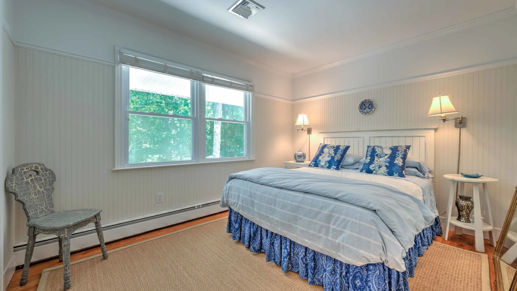 Un dormitorio con una cama cubierta de azul y una ventana grande.