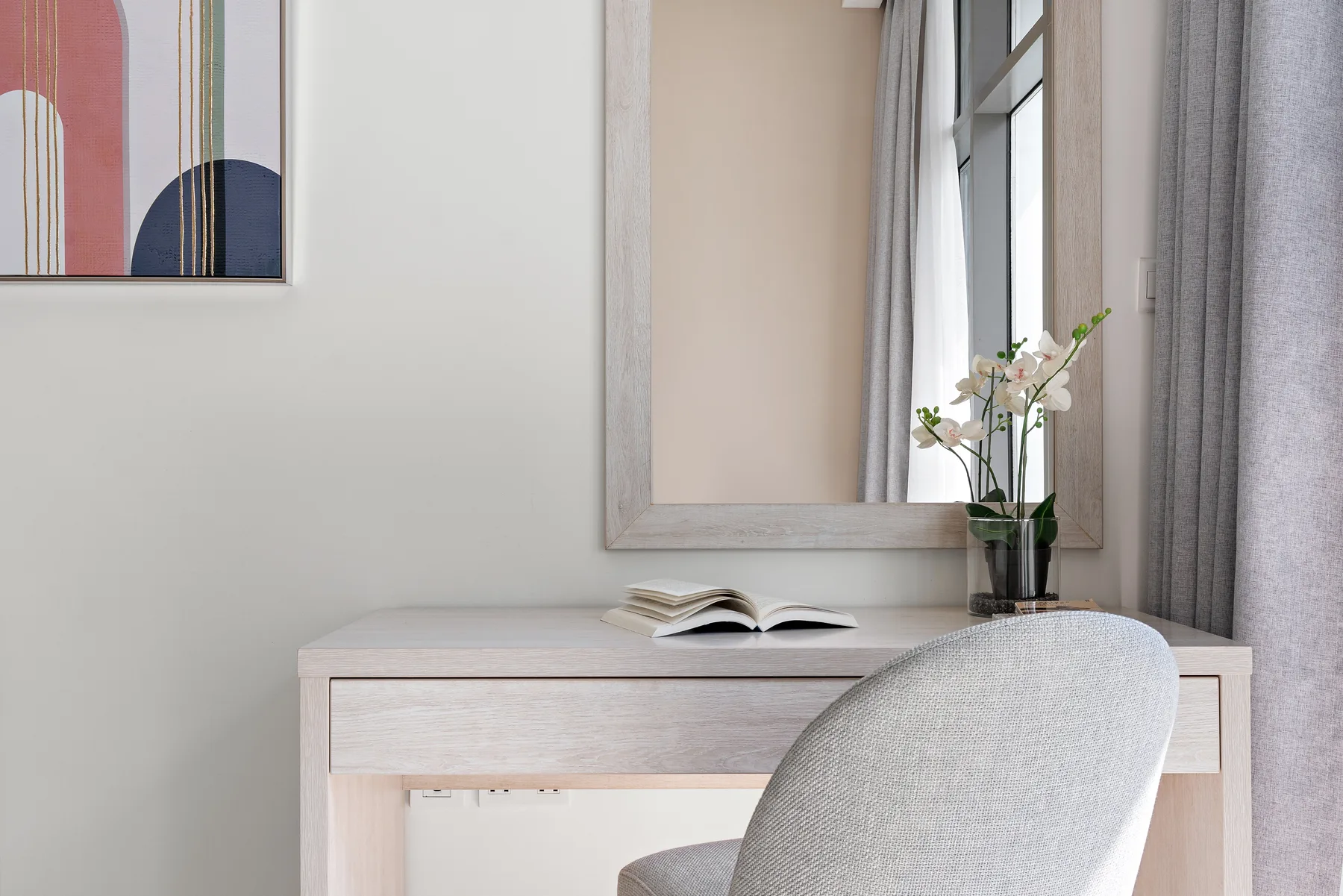 Un rincón luminoso con escritorio, silla, libro abierto y flores junto a una ventana.