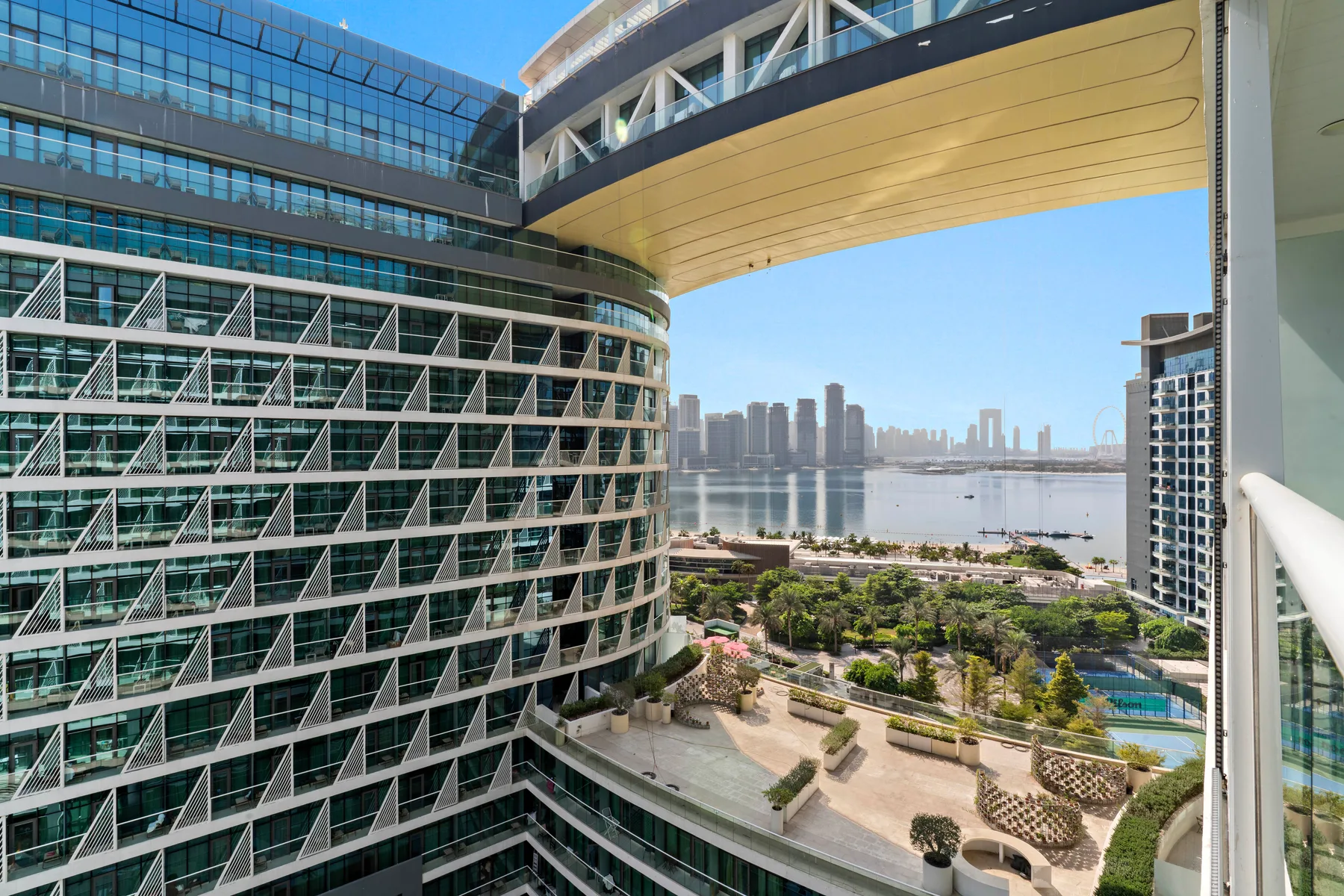 Edificios modernos de vidrio dan a una zona costera y una terraza ajardinada.