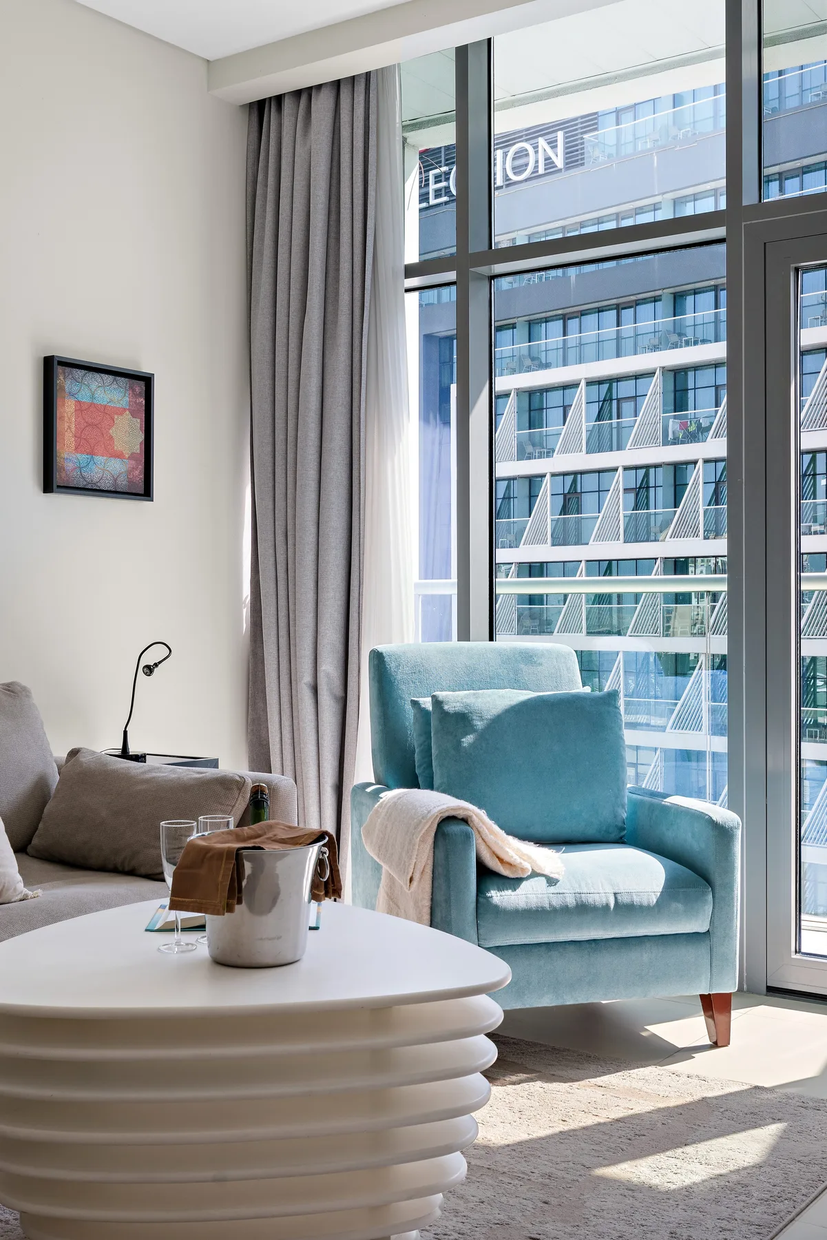 Una sala luminosa con asientos junto a grandes ventanas con vista a edificios cercanos.