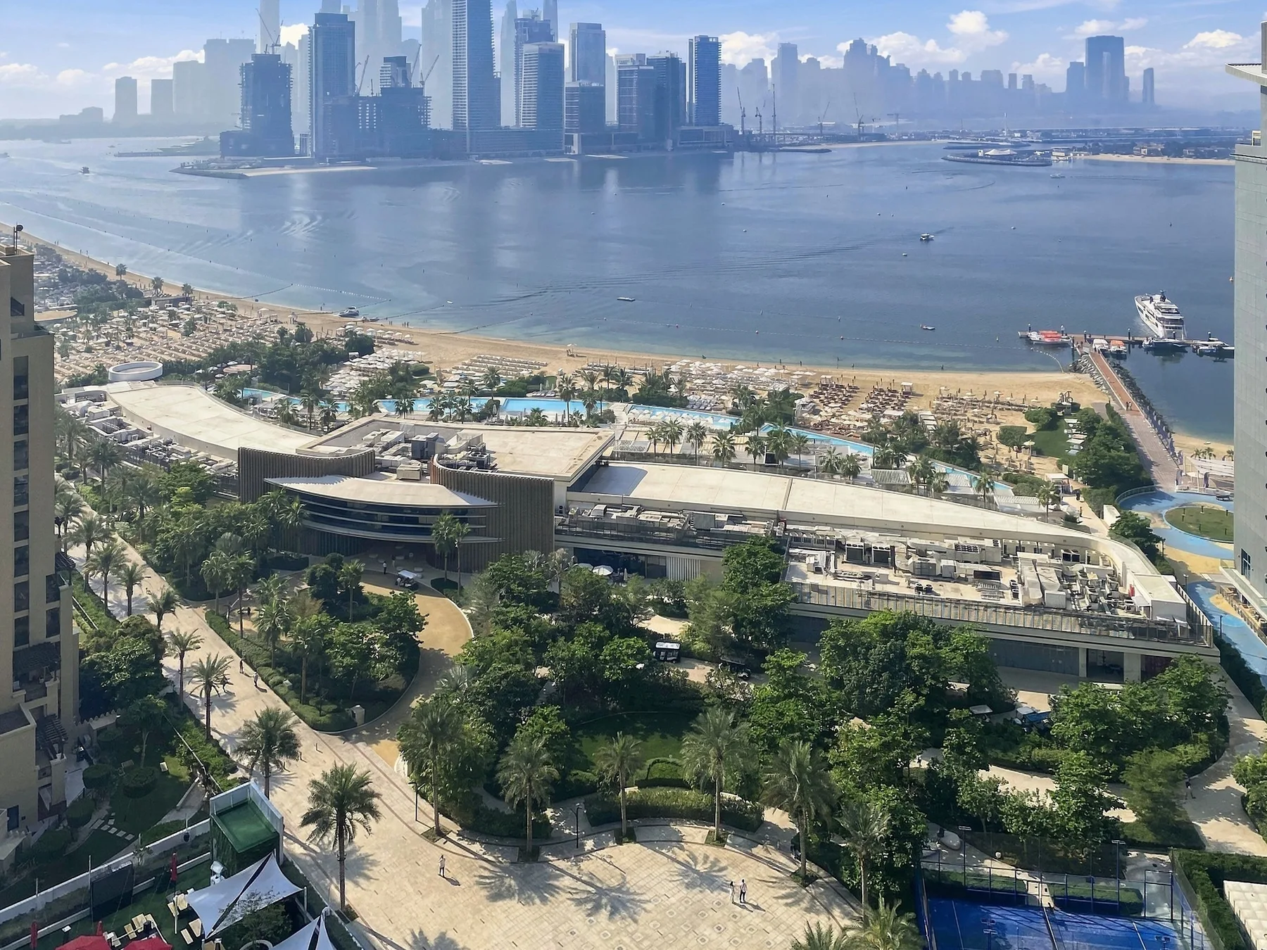 Vista aérea de un parque junto al agua, una playa y el perfil urbano al otro lado de la bahía.