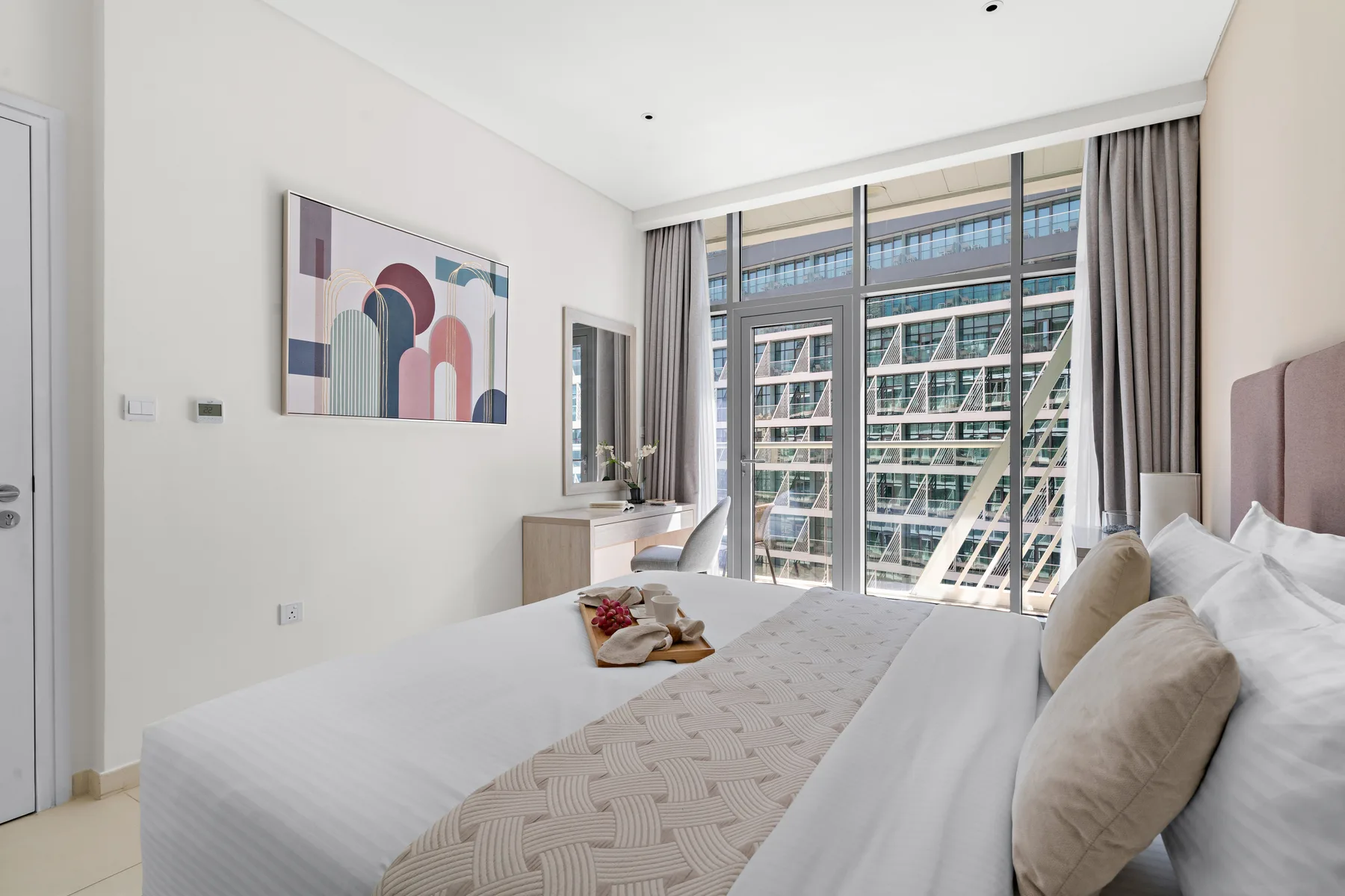 Un dormitorio luminoso con una cama grande junto a ventanales.