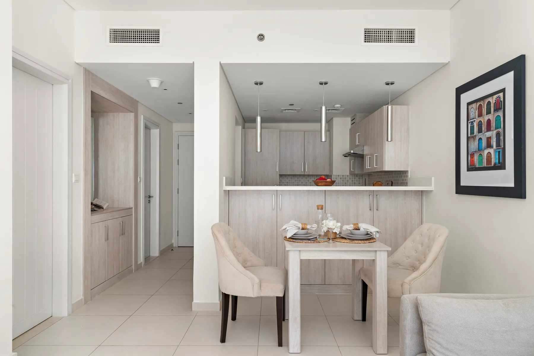 Un comedor con una mesa y asientos tapizados junto a una cocina abierta.