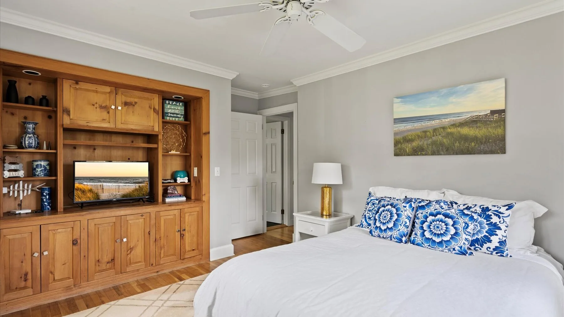 A bedroom with a large bed and blue patterned pillows beside built-in wooden cabinetry.