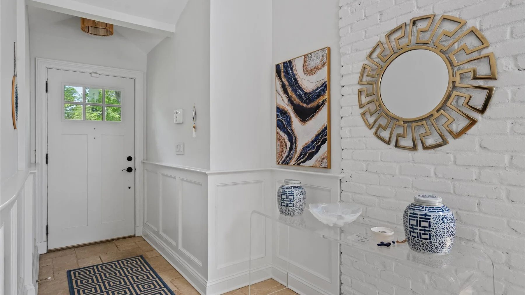 A bright white entryway with a paneled door and decorative wall art.