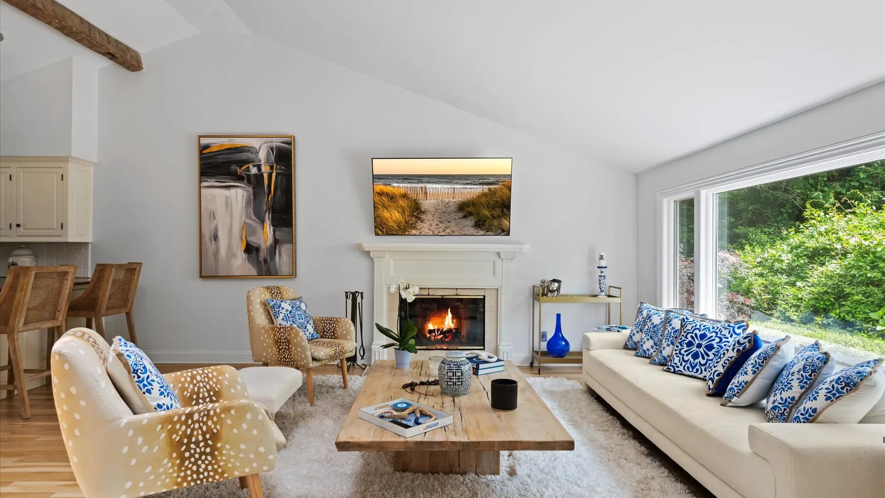 Una sala luminosa con chimenea, asientos y grandes ventanas con vistas a la vegetación.