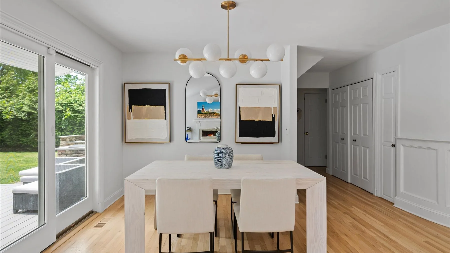 A bright dining area with a long table and upholstered seating beside large windows.