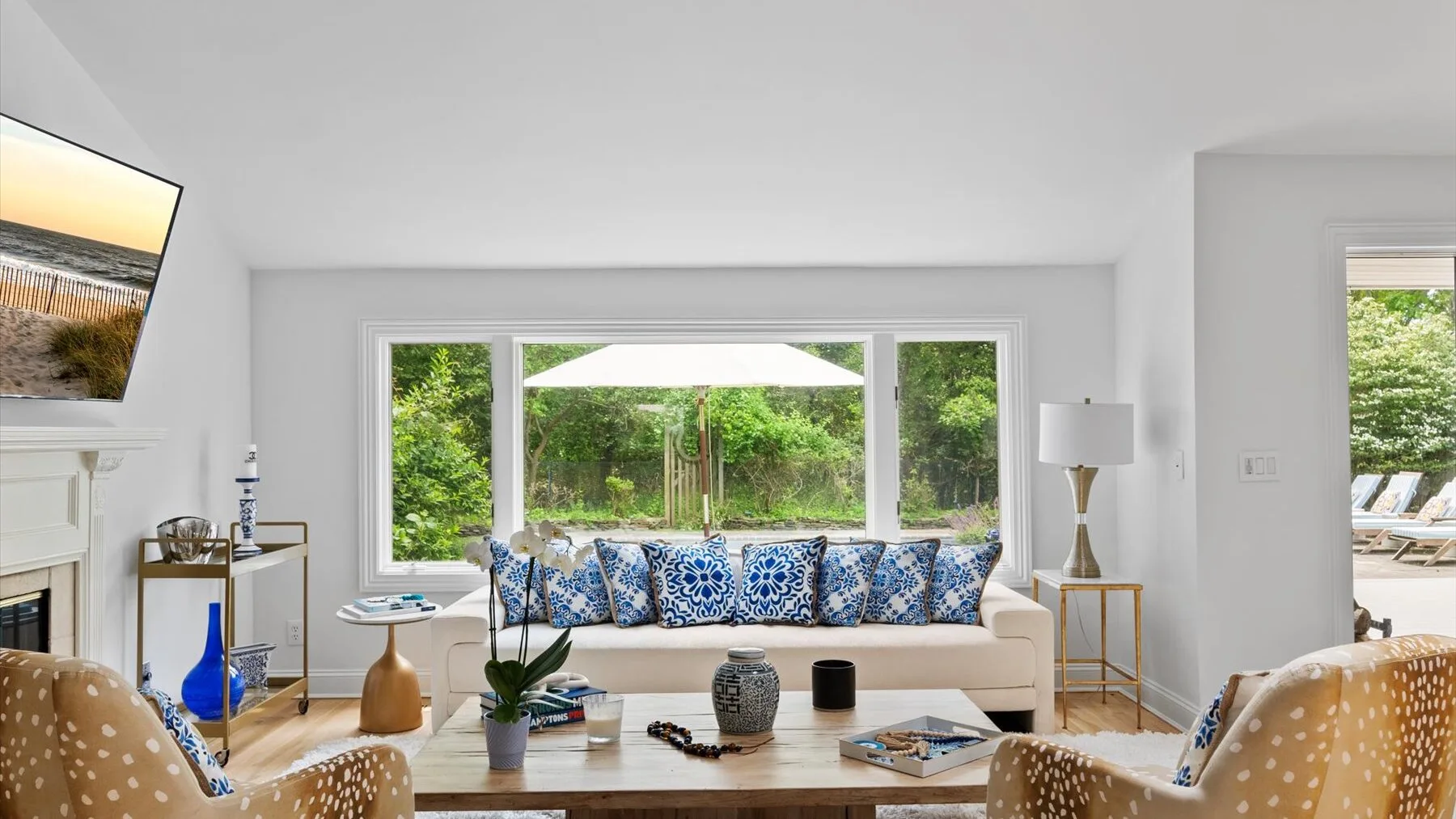 A bright living room with seating arranged around a coffee table and a large garden-facing window.