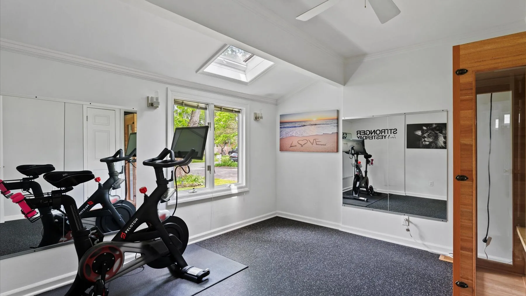 A bright exercise room with stationary bikes and a large wall mirror.