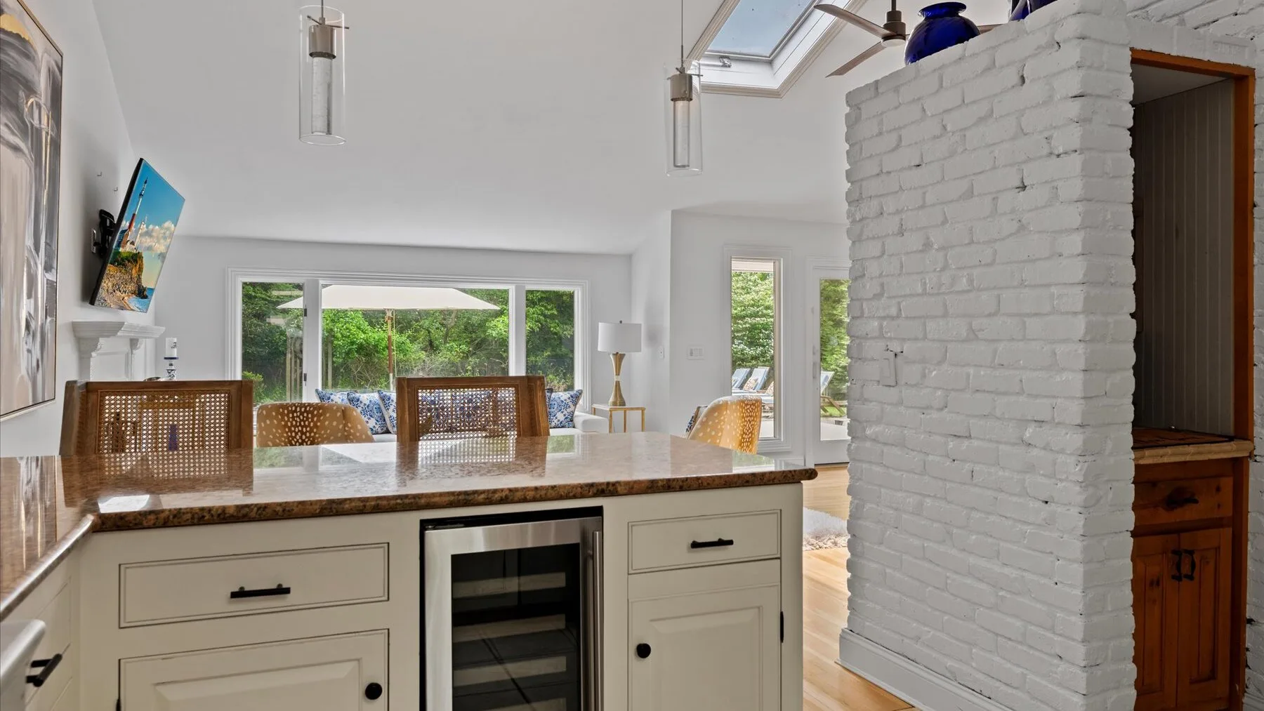 A bright kitchen with a central island and large windows overlooking greenery.