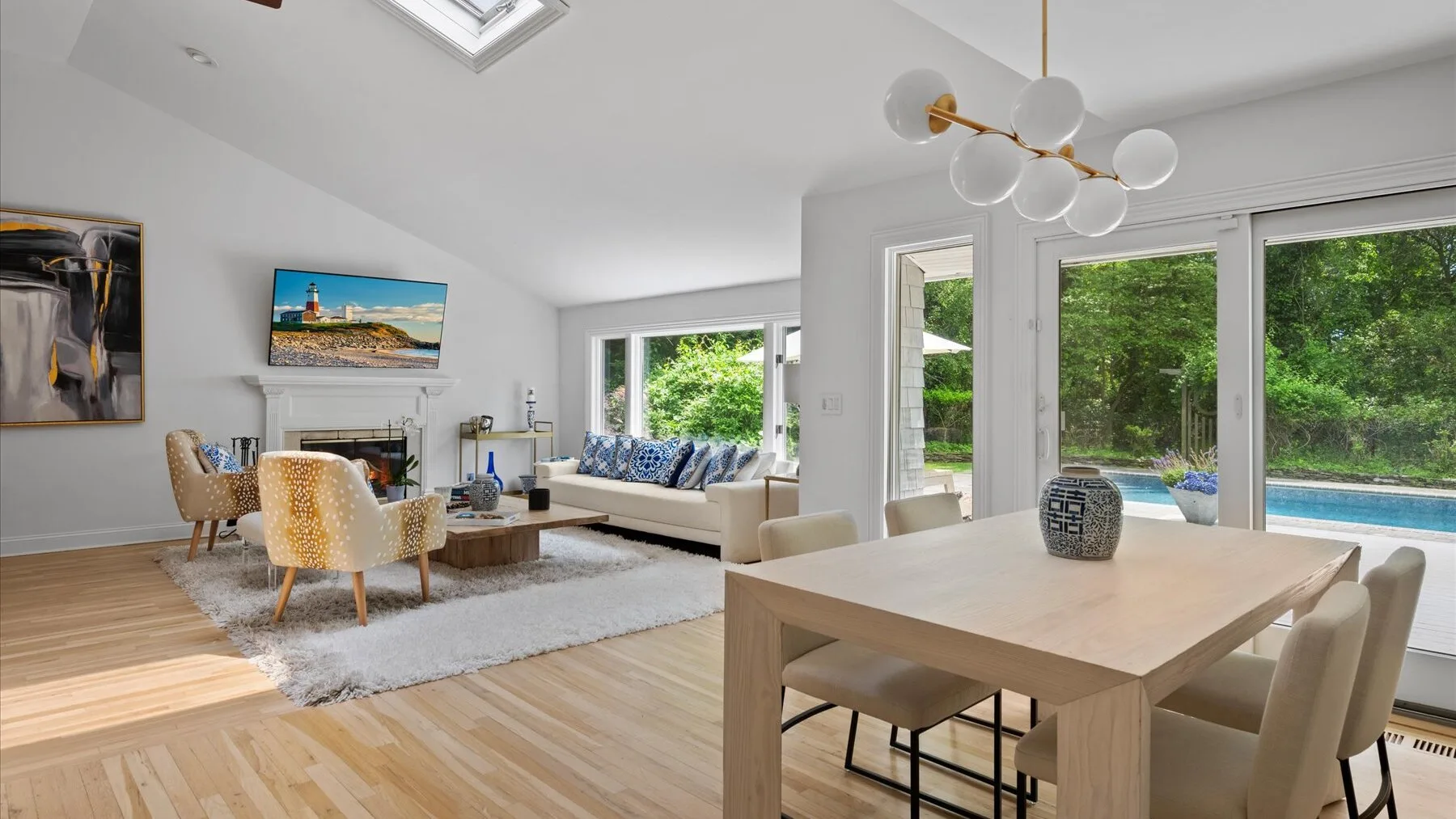 A bright open-plan living and dining area with large windows overlooking greenery.