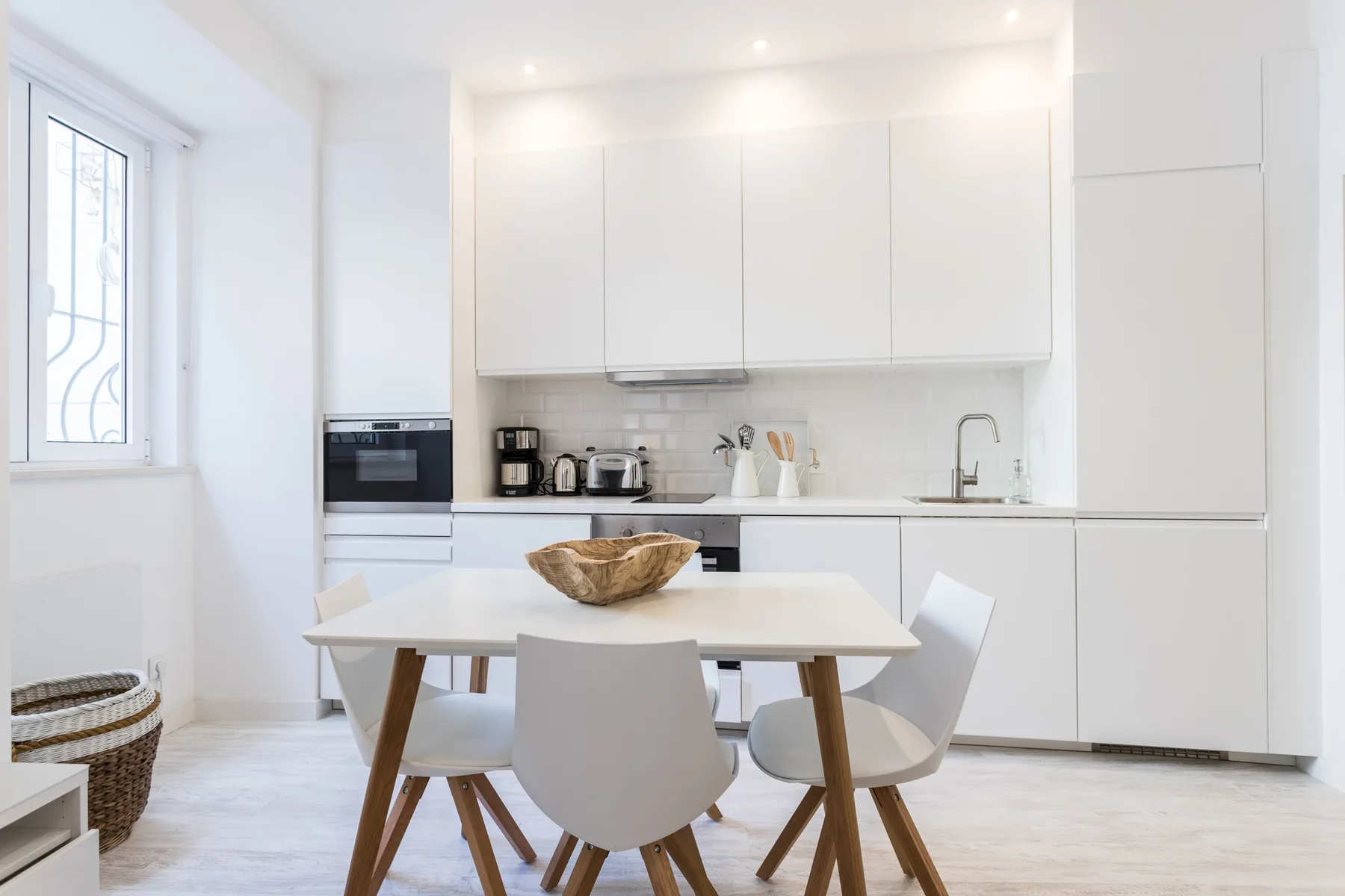 Cocina y comedor luminosos en tonos blancos, con mesa y sillas.