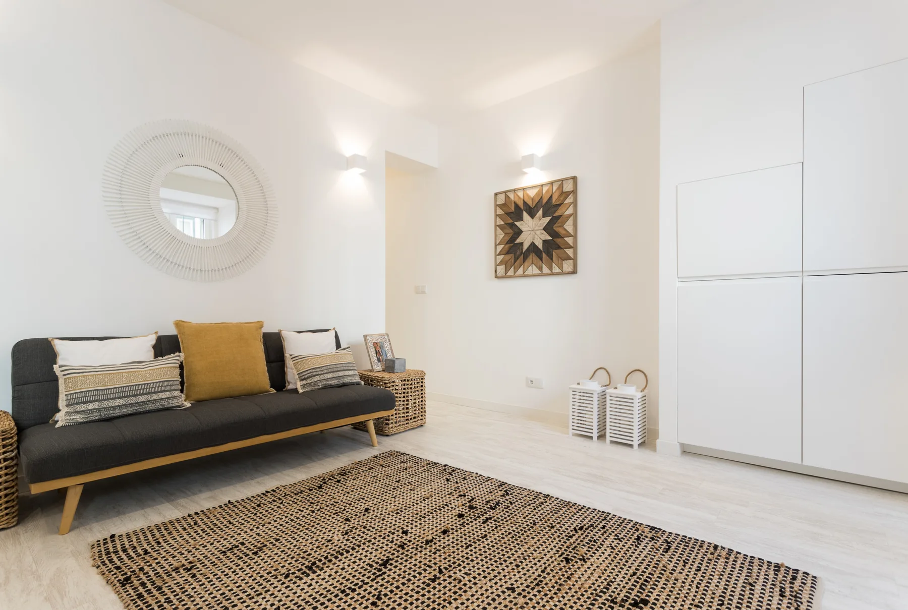 Living room with a dark sofa, patterned rug, and wall mirror.