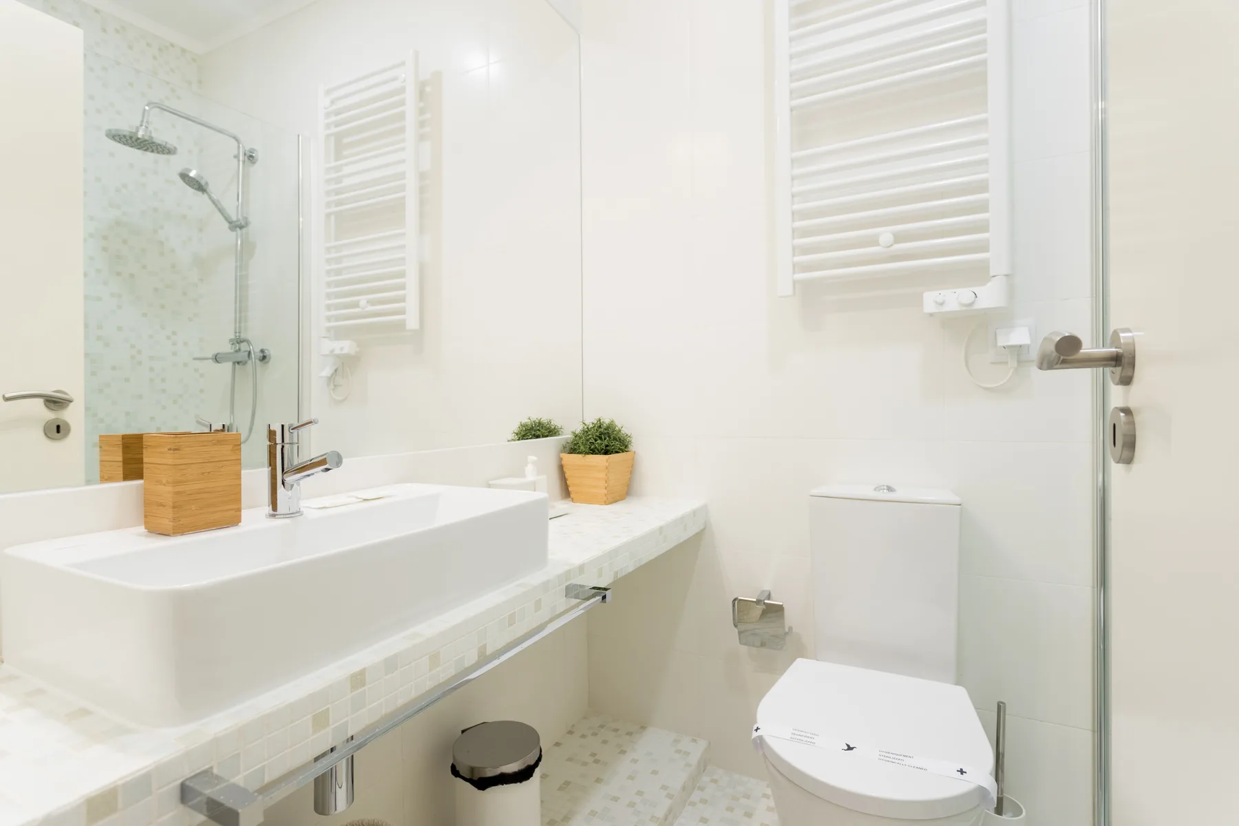 A bright bathroom with a sink, toilet, and glass shower.