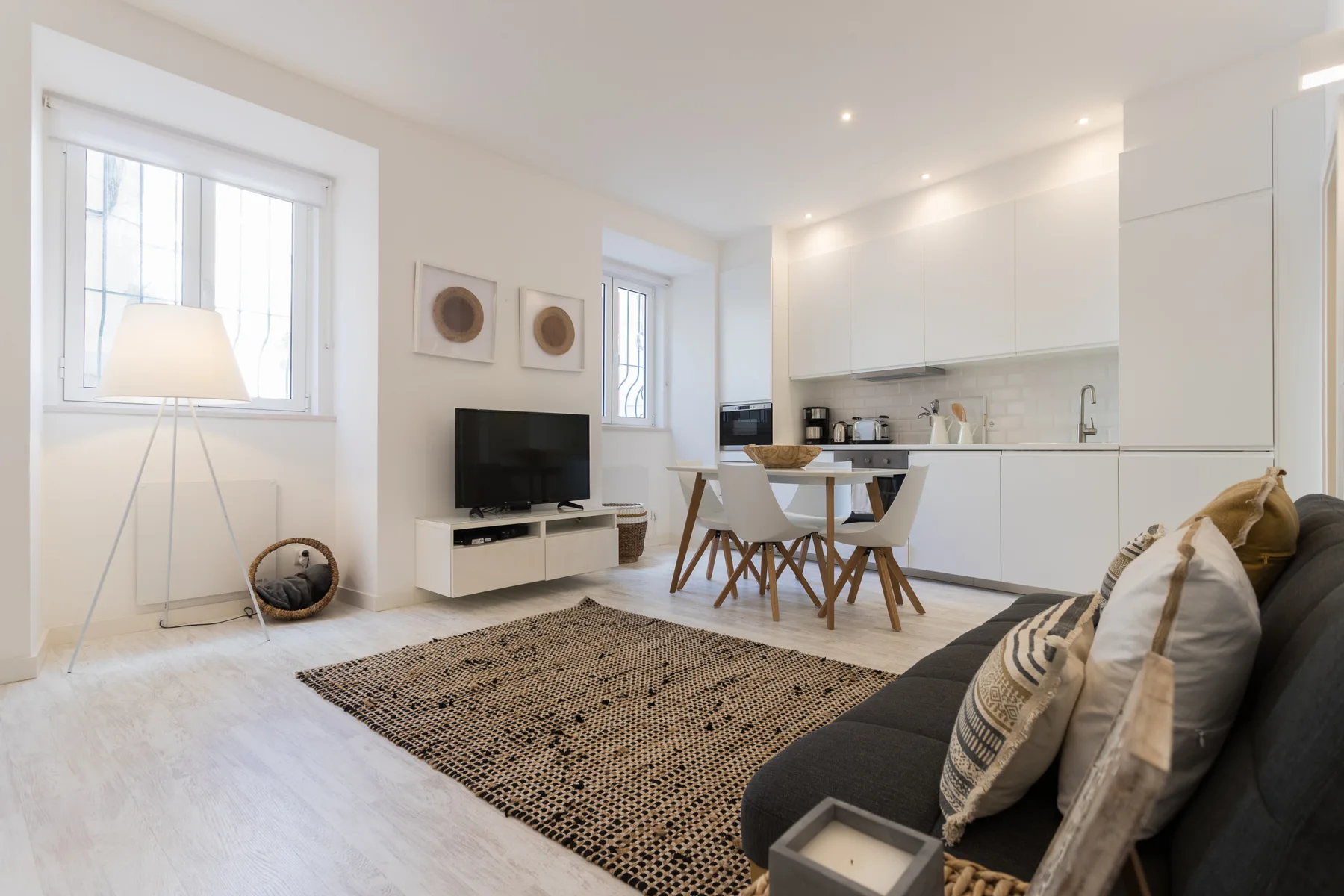 A bright living room with seating, a rug, and an open kitchen.