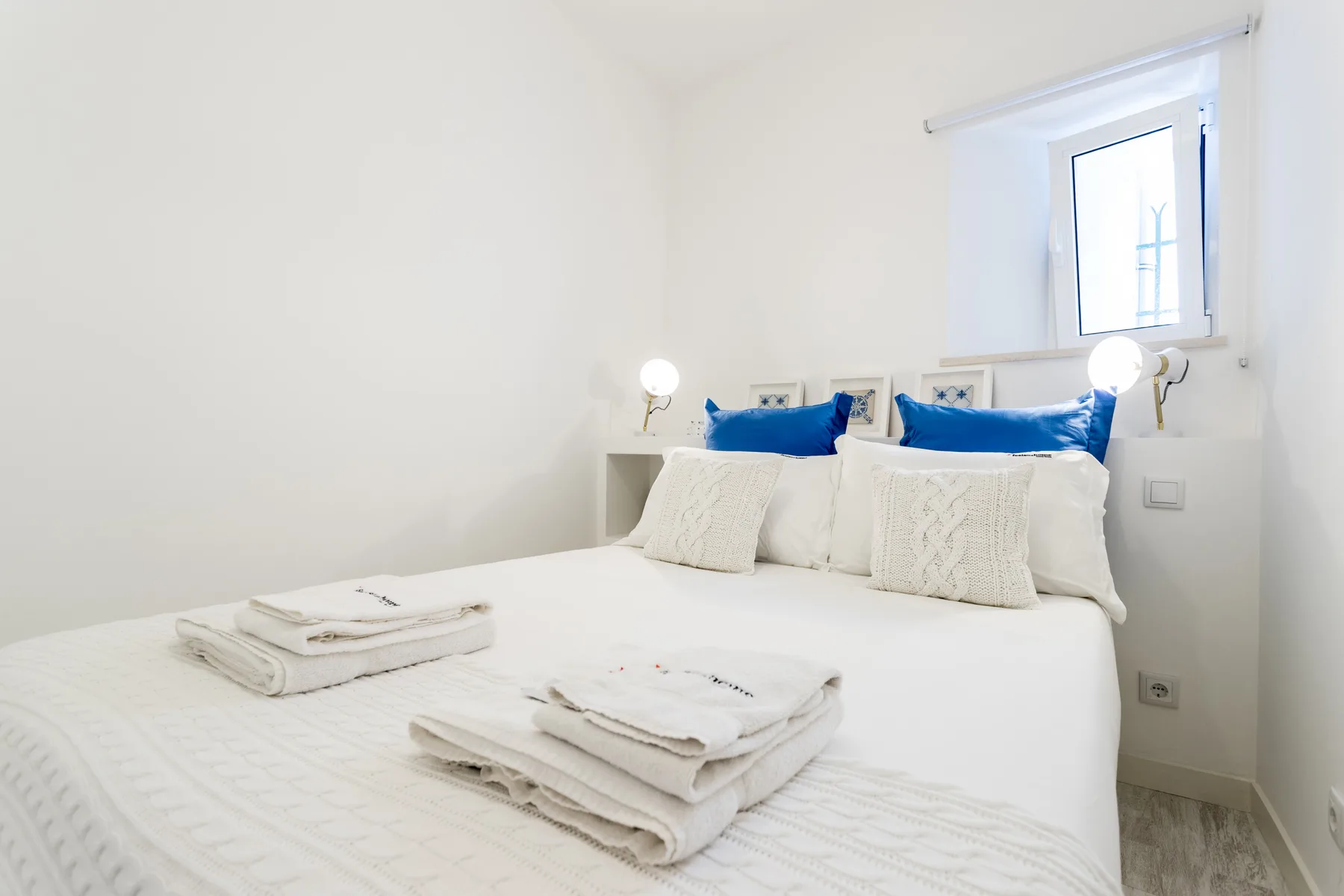 A bedroom with a neatly made bed and folded towels.