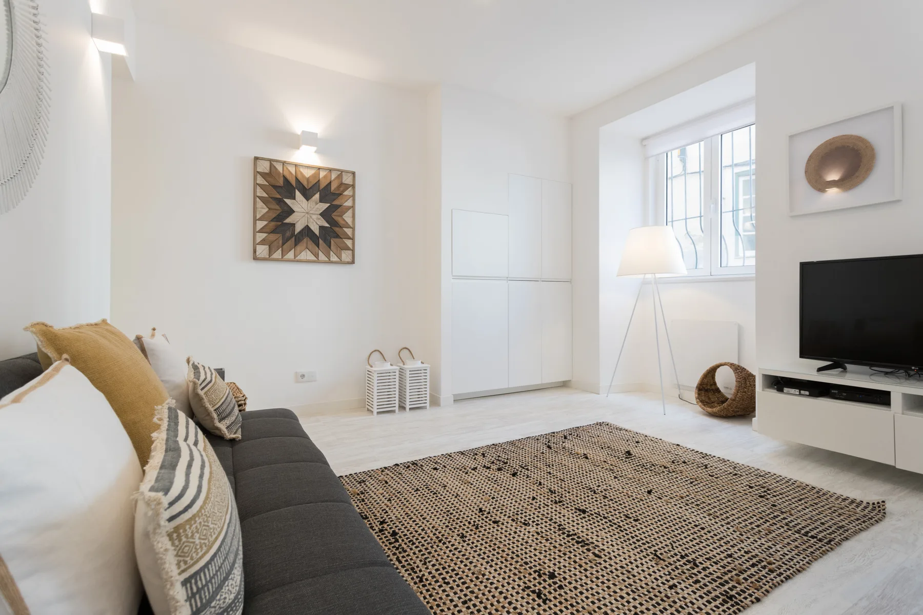 Living room with seating, a rug, and a television beside a window.