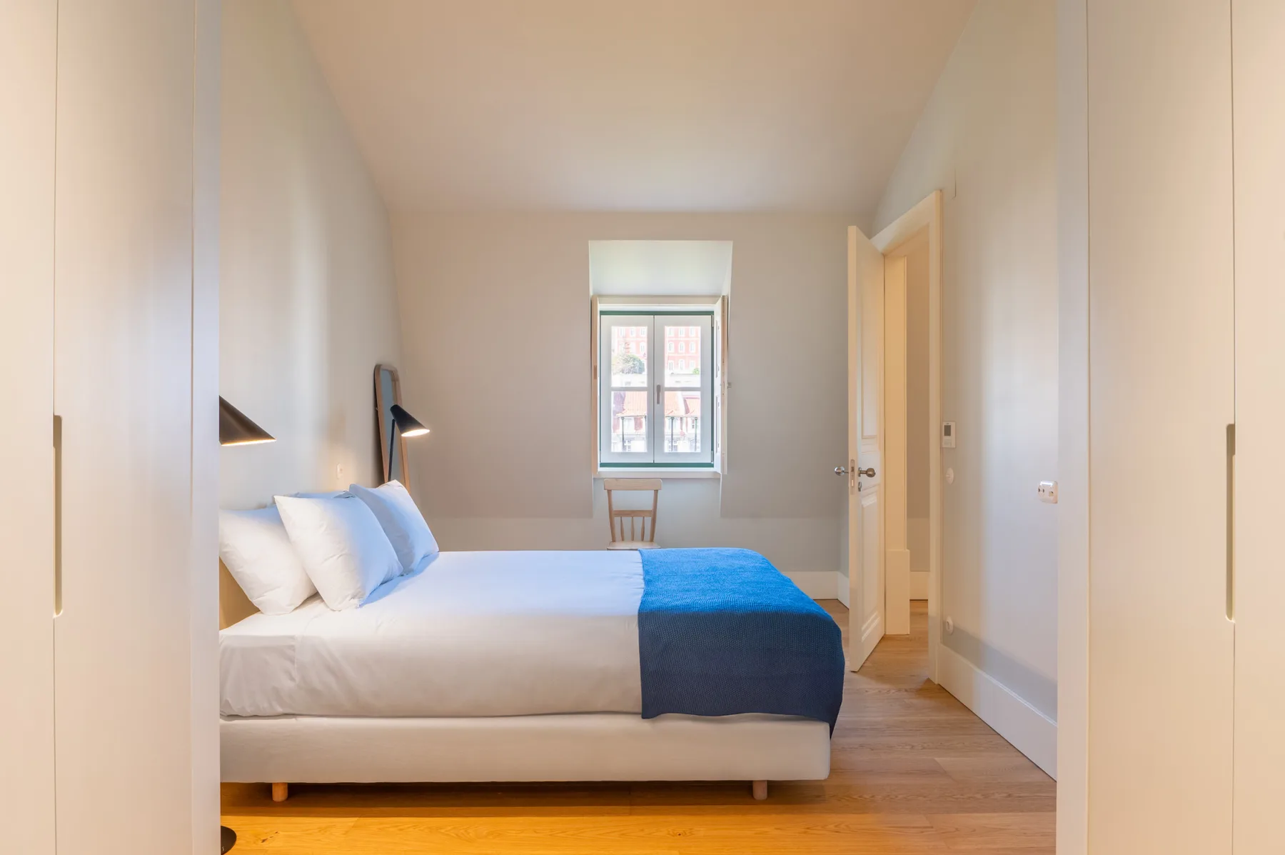 Un dormitorio luminoso con una cama y una ventana al fondo.