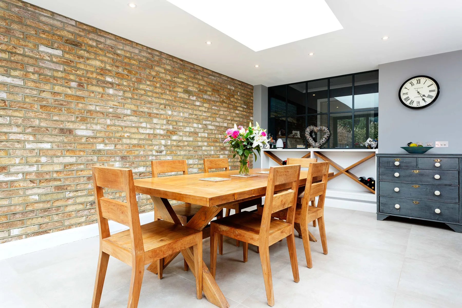 A dining area with a wooden table and chairs beside a brick wall.