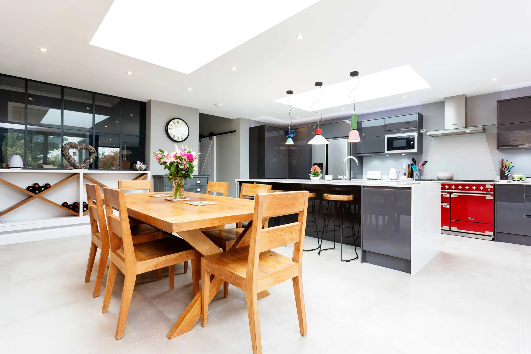 A bright open-plan kitchen and dining area with a wooden table and island.