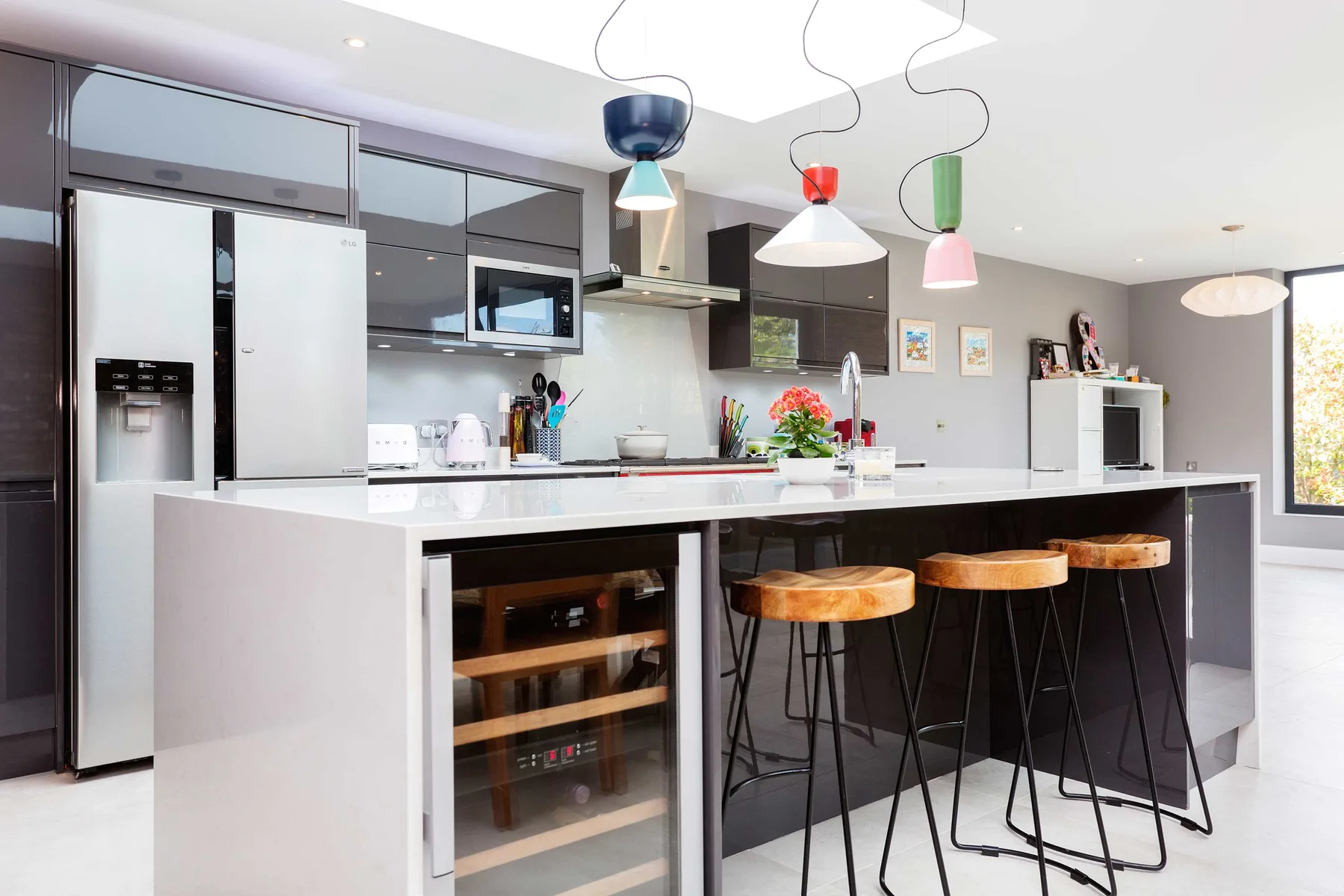 A modern kitchen with a white island, bar seating, and pendant lights.