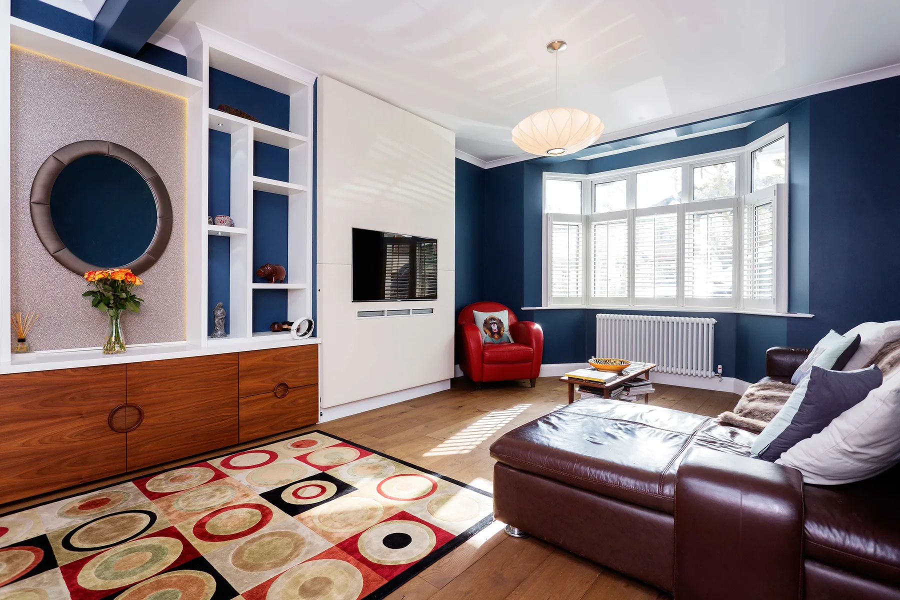 A living room with dark seating, built-in shelving, and a bay window.