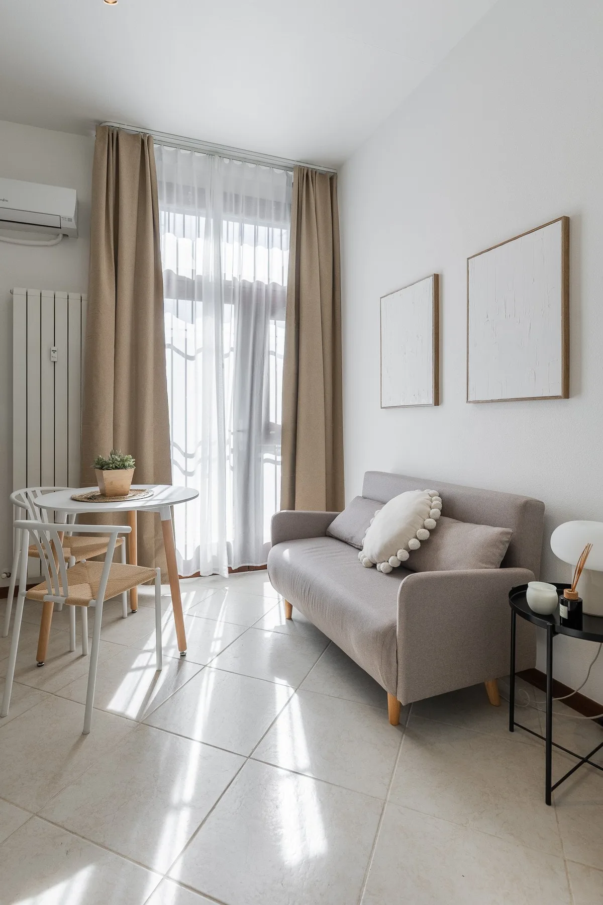 A bright living area with seating beside a dining table and large windows.