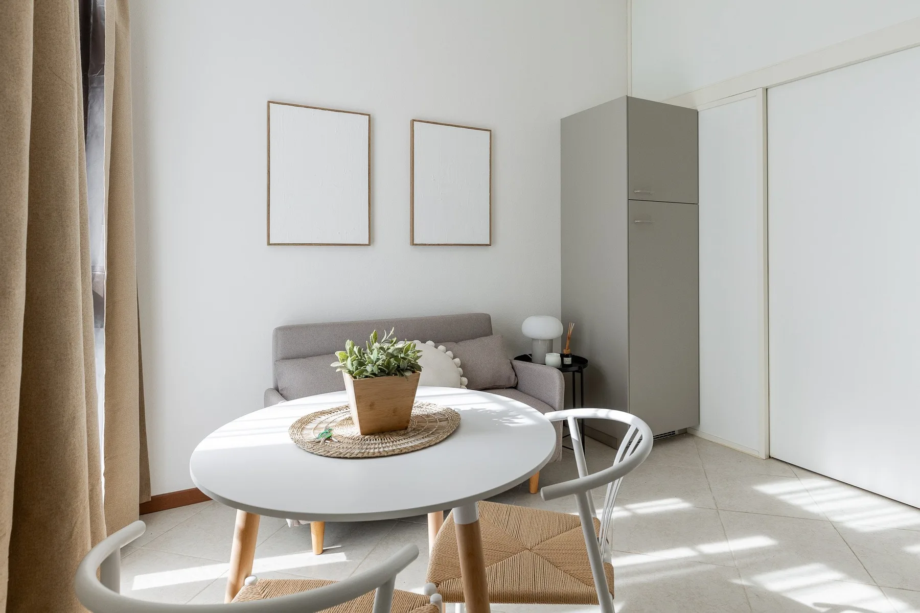 A bright dining area with a round table, seating, and a plant centerpiece.
