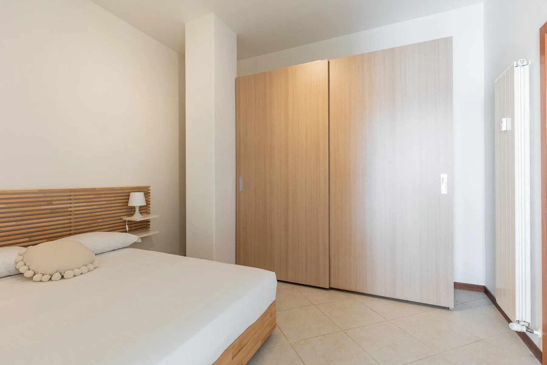 A bedroom with a bed beside large wooden sliding doors.