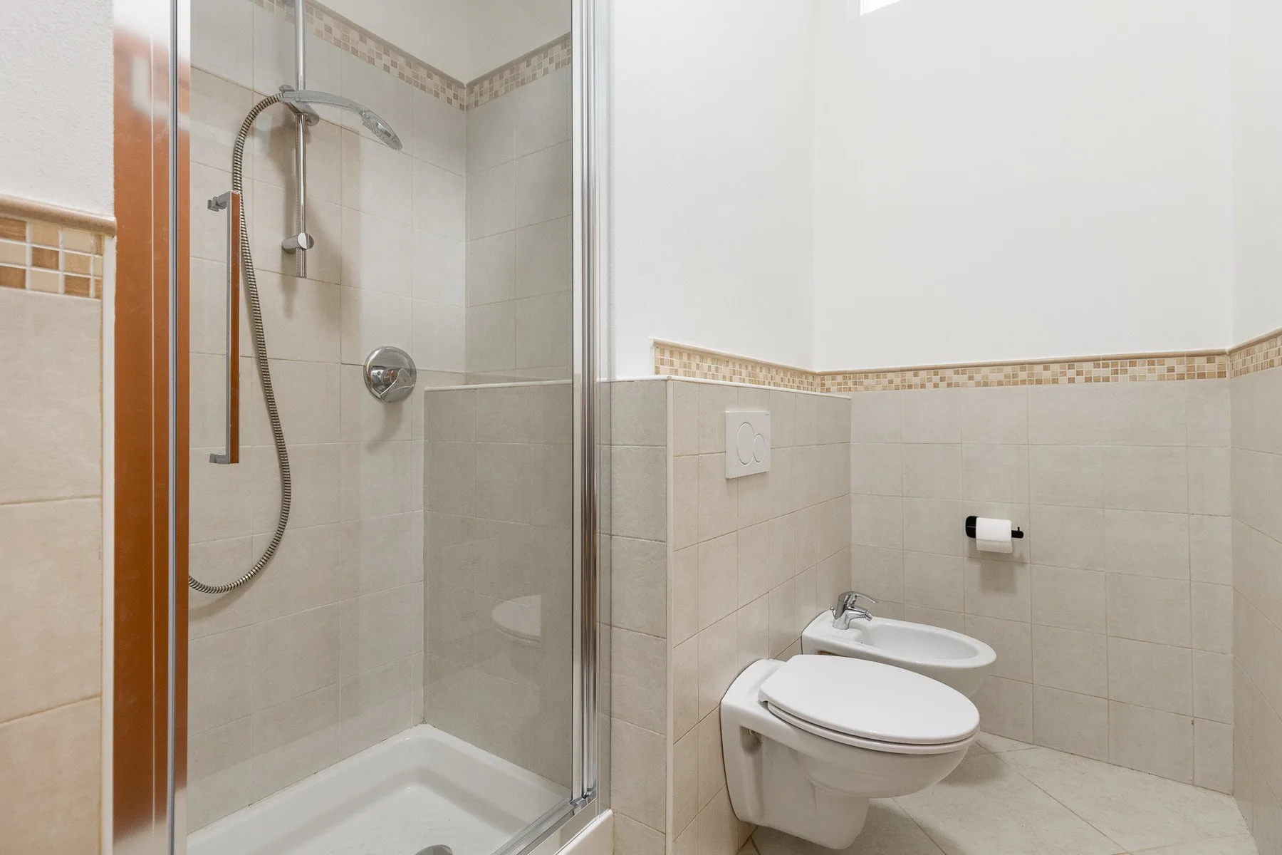 A tiled bathroom with a shower, toilet, and sink.