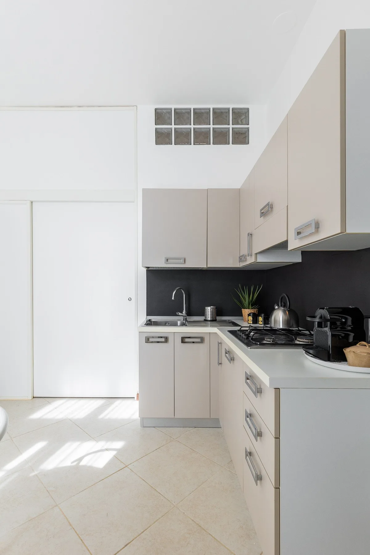 A bright kitchen with light cabinets, a dark backsplash, and a countertop.