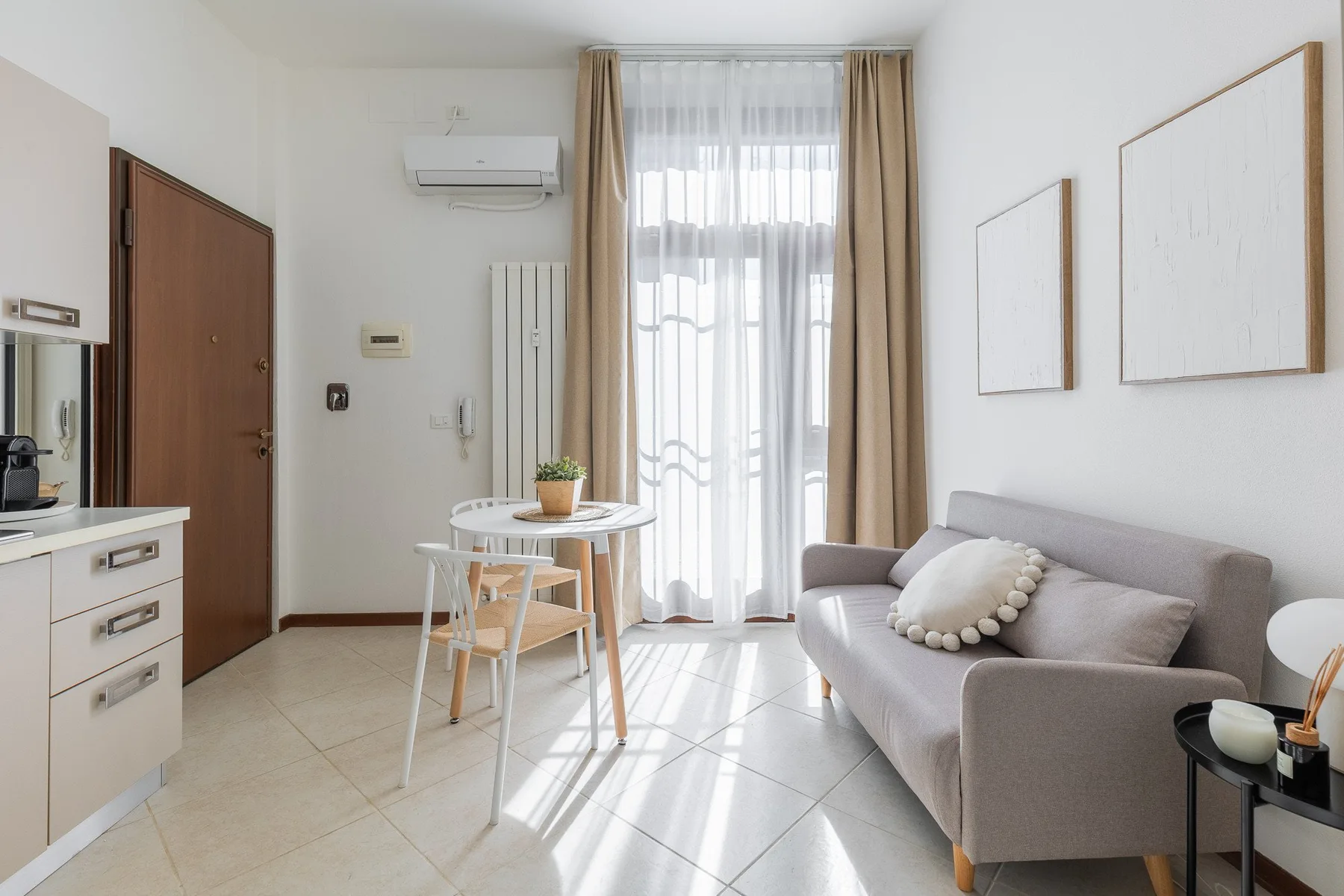 A bright living room with a gray sofa and a small dining table by the window.
