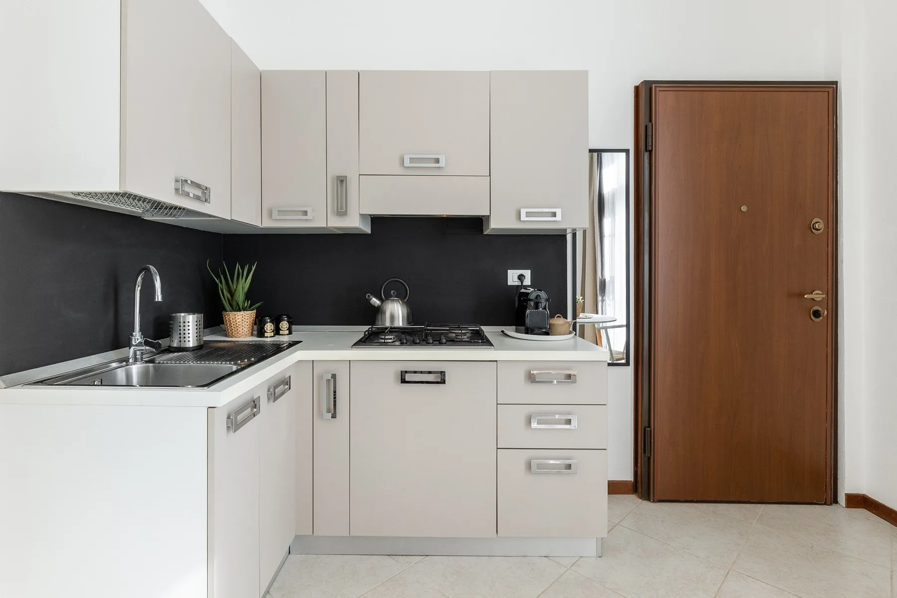 Una cocina moderna con gabinetes blancos, salpicadero oscuro y una estufa sobre la encimera.
