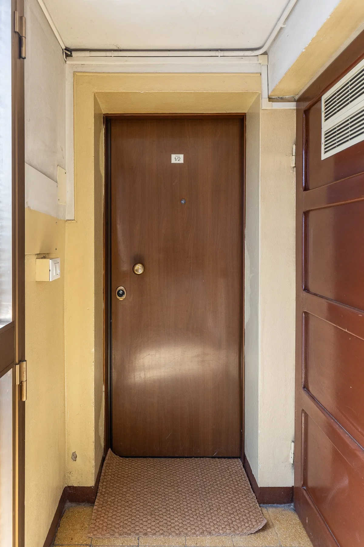 A brown entry door opens onto a small tiled interior landing.