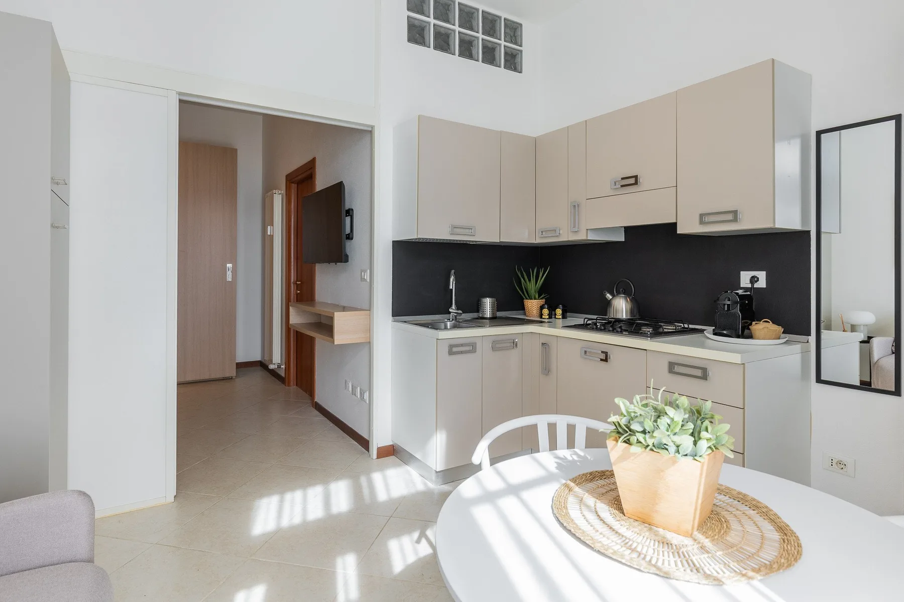 Una cocina luminosa con gabinetes claros, salpicadero oscuro y mesa redonda.