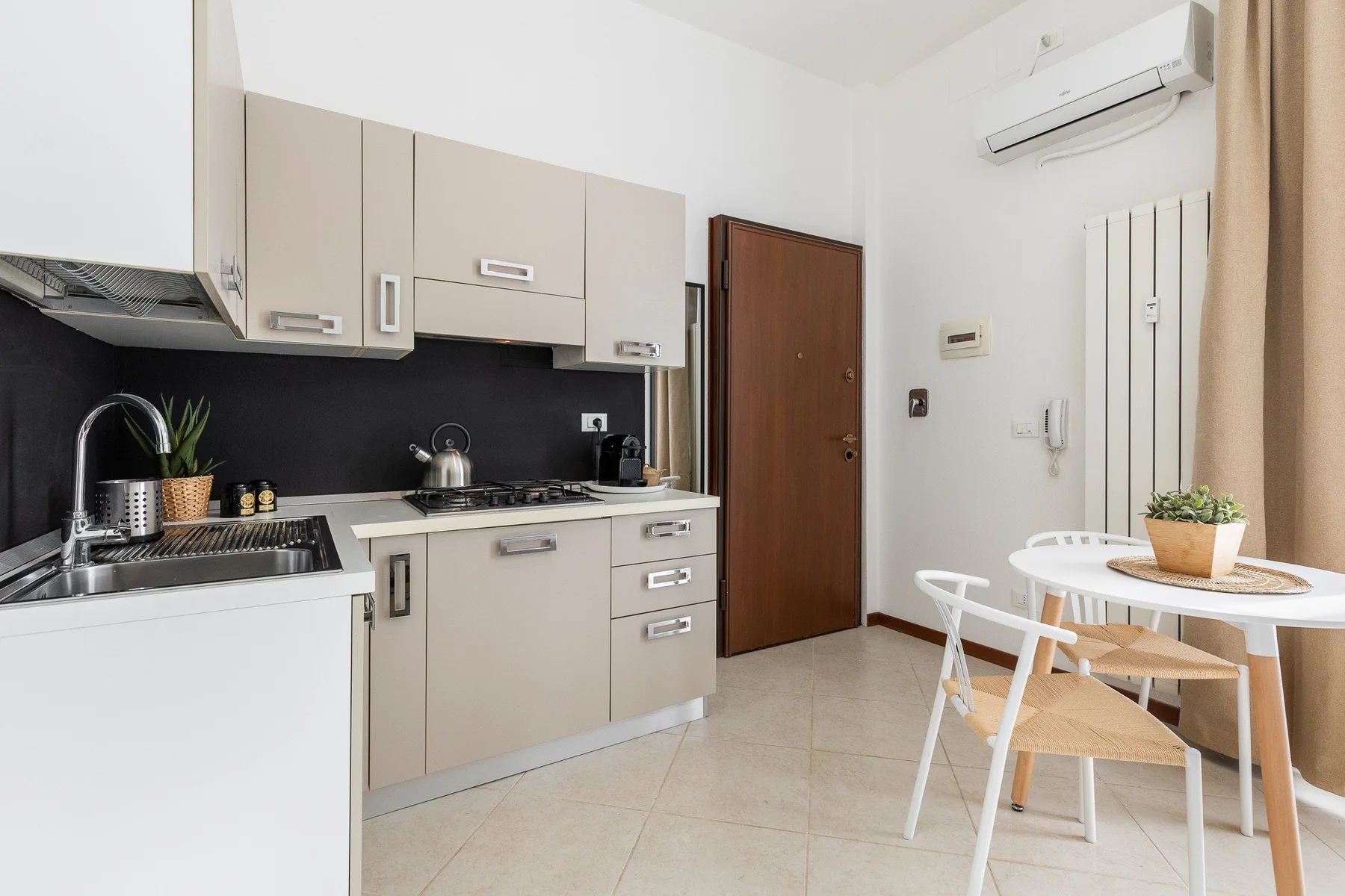 A compact kitchen opens onto a dining area with a small table and chairs.