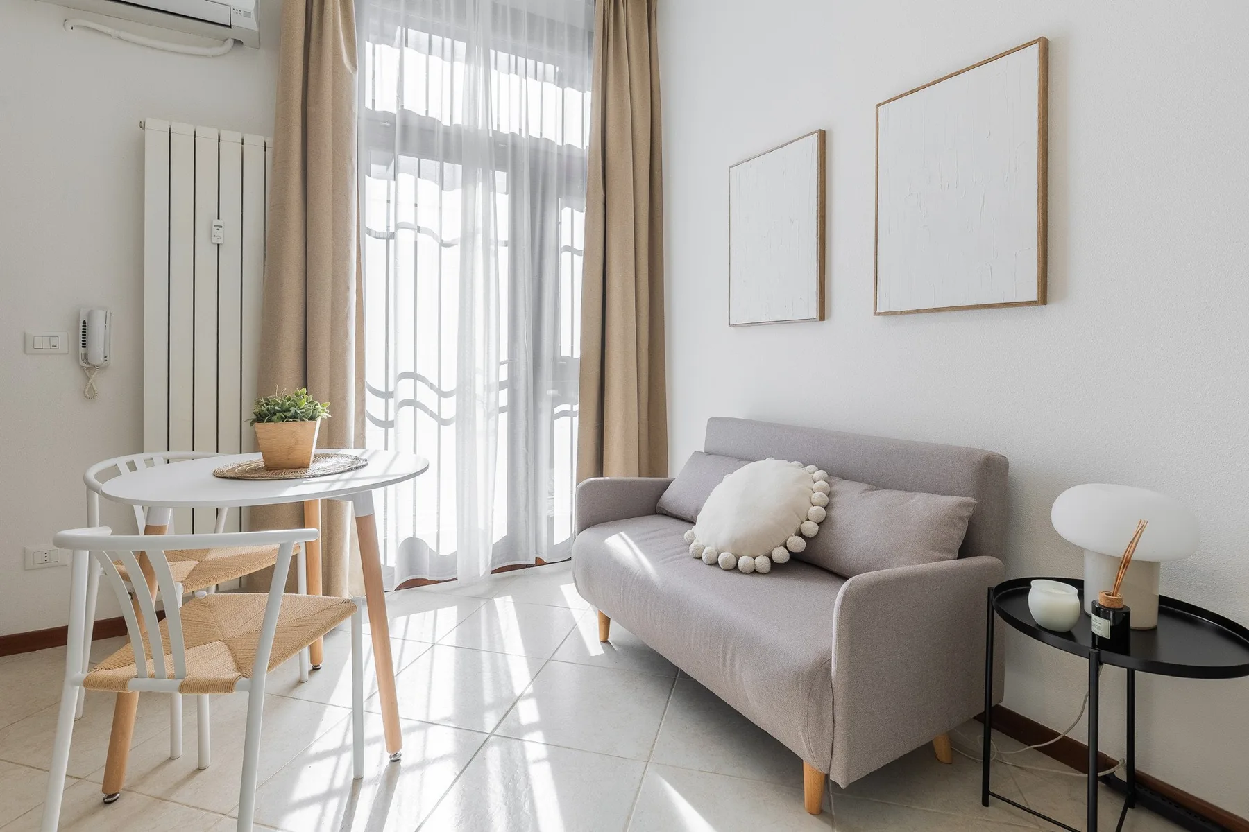 A bright sitting area with a gray sofa beside a small dining table.