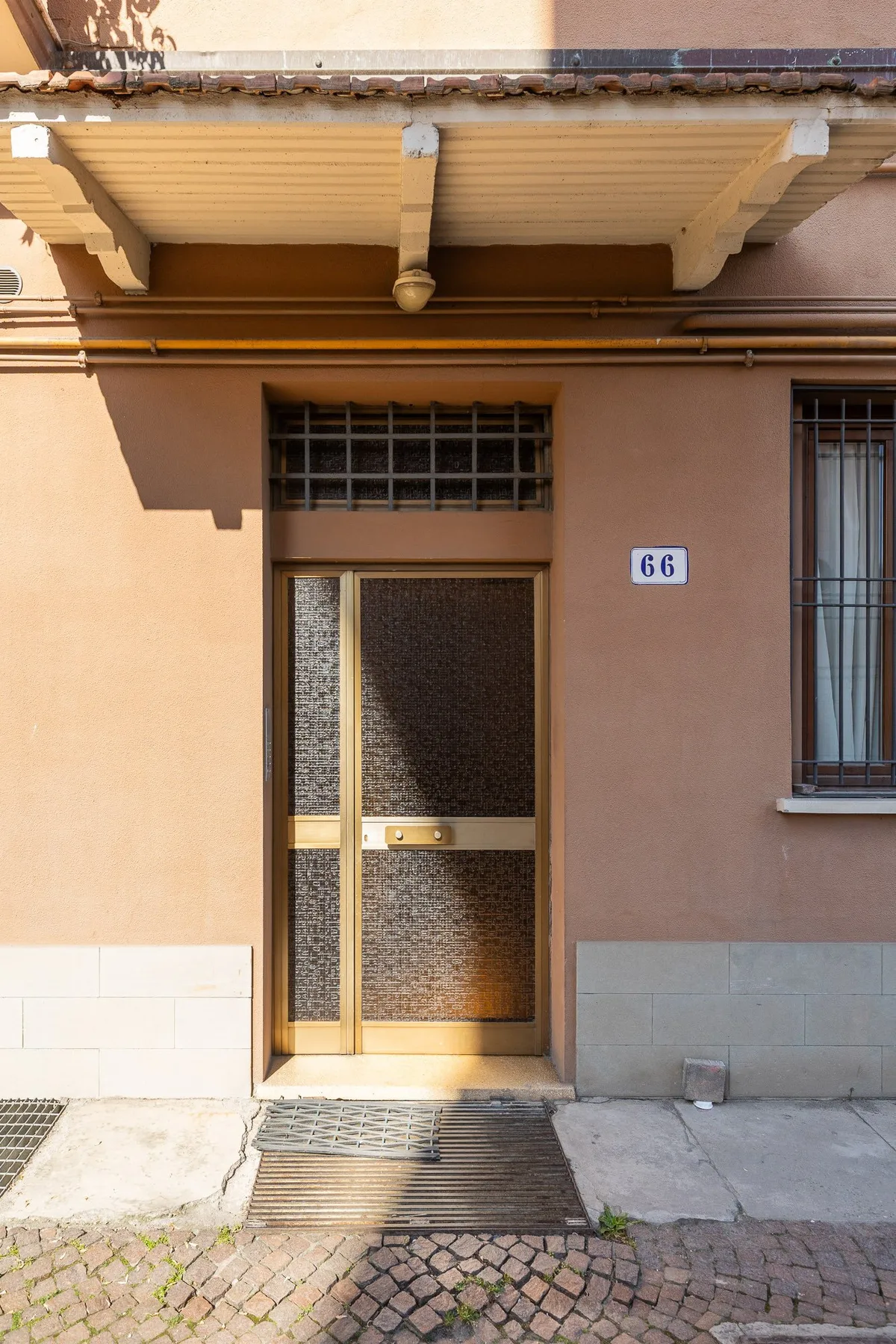 A building entrance with a metal-framed door and barred windows.