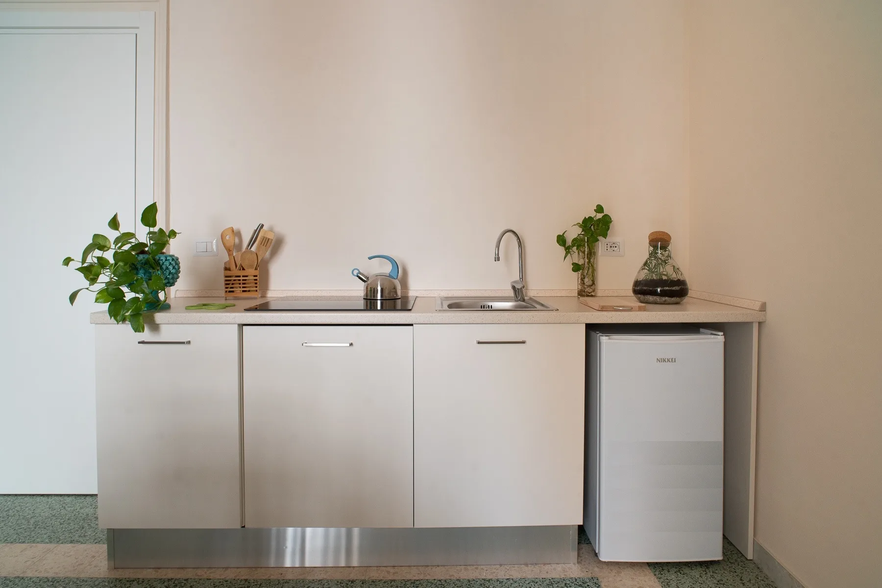A compact kitchenette with a sink, countertop, and small refrigerator.