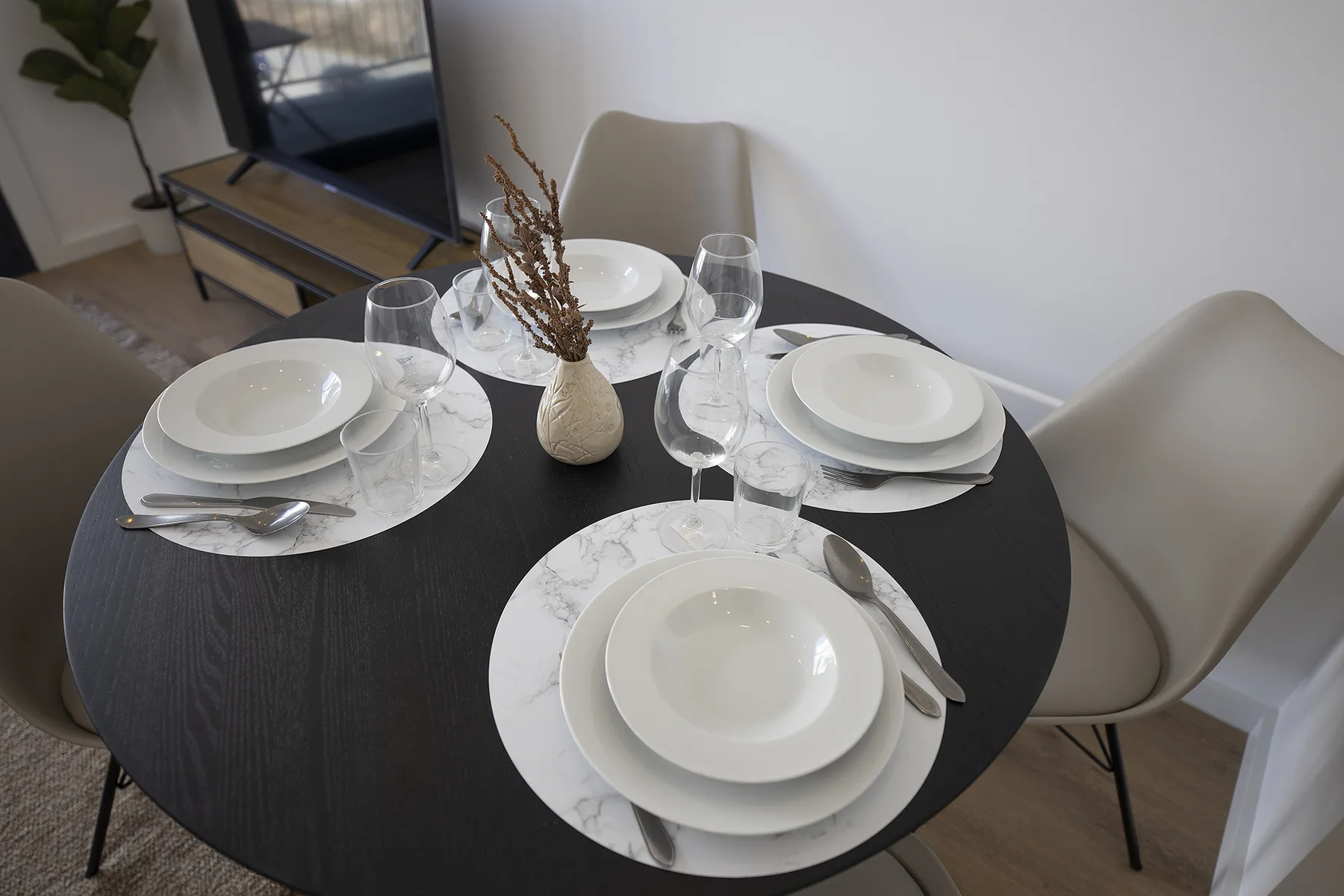 Comedor con una mesa redonda preparada con platos y vasos.