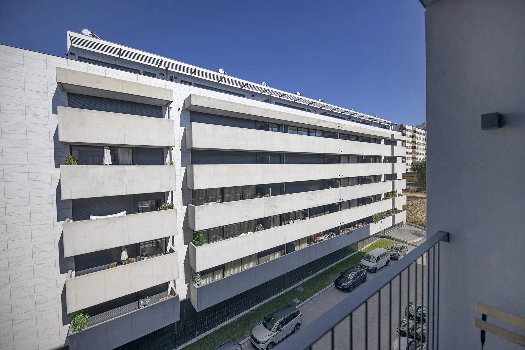 A balcony overlooks a modern apartment building and the street below.